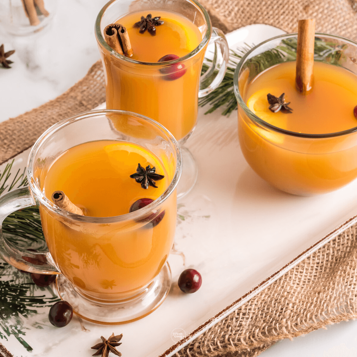Hot Wassail in pretty glass mugs garnished with cinnamon sticks and star anise.