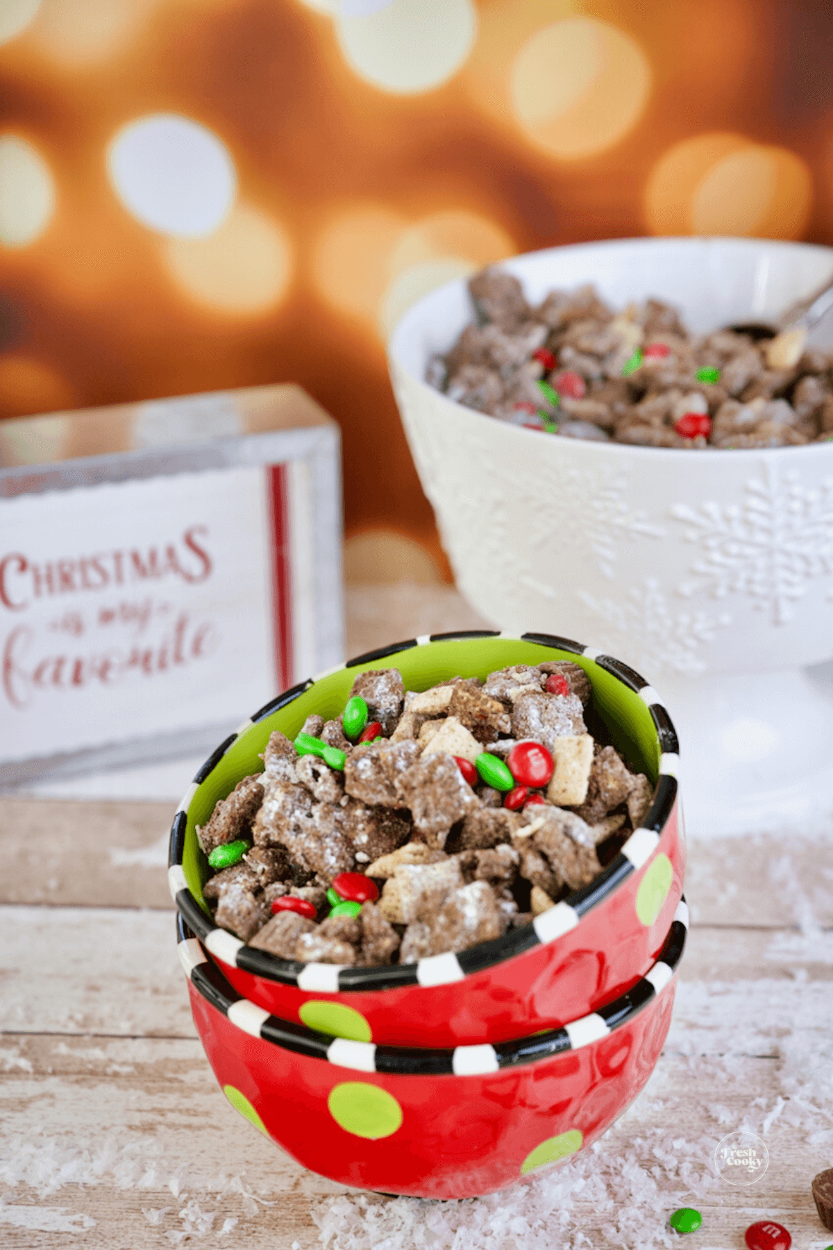 Reindeer Puppy Chow in cute Christmas bowls with rest of muddy buddy chex mix in background.