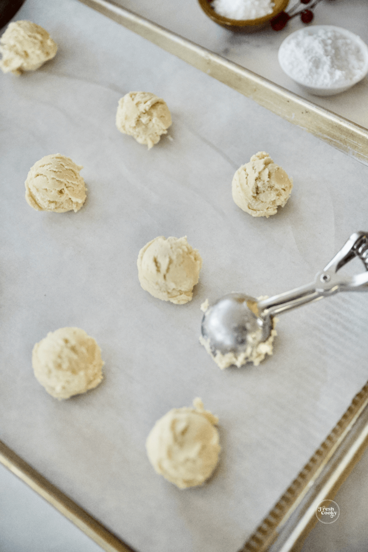 Scooping small balls of cookie dough onto parchment lined baking sheets.
