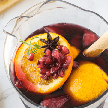 Pitcher filled with spiced holiday sangria ingredients.