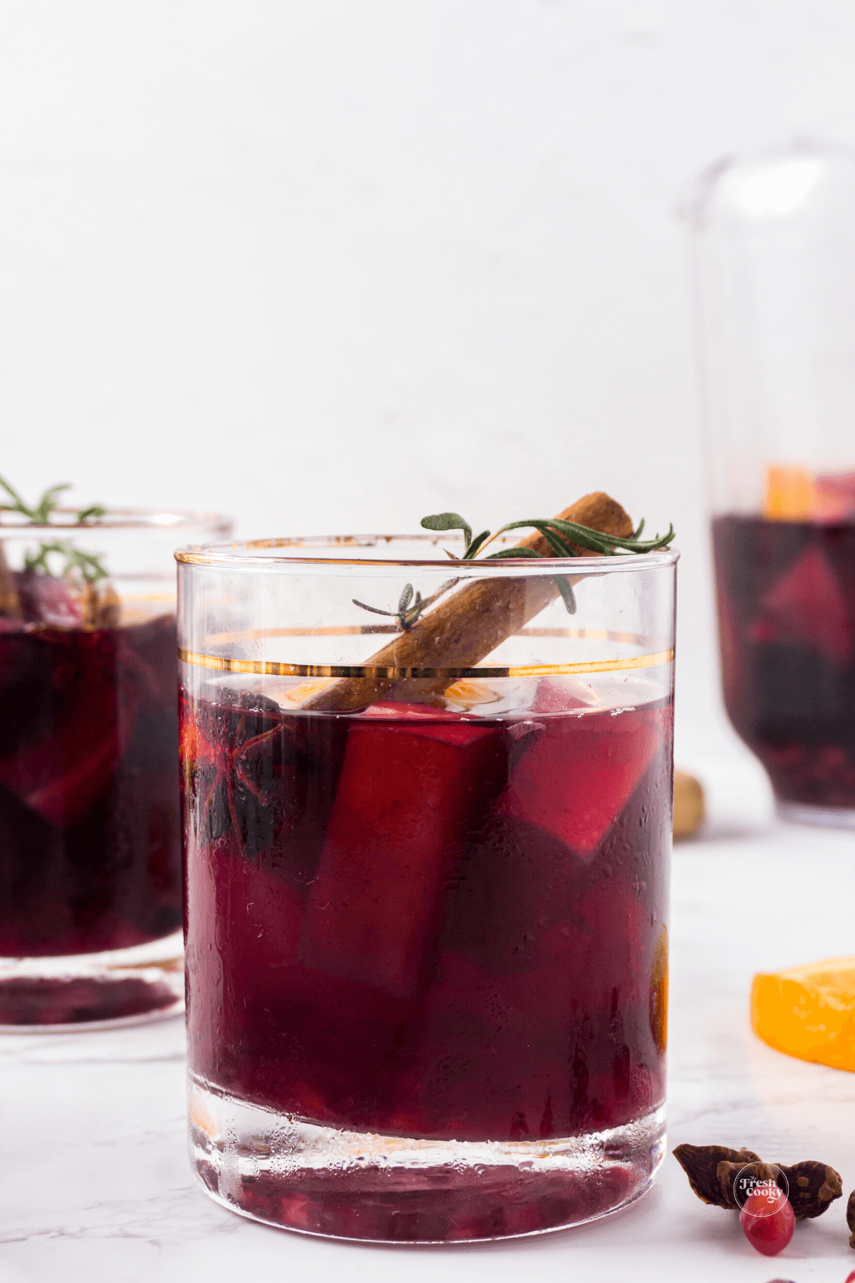 Spiced holiday sangria in pretty glass with cinnamon stick and sprig of rosemary.