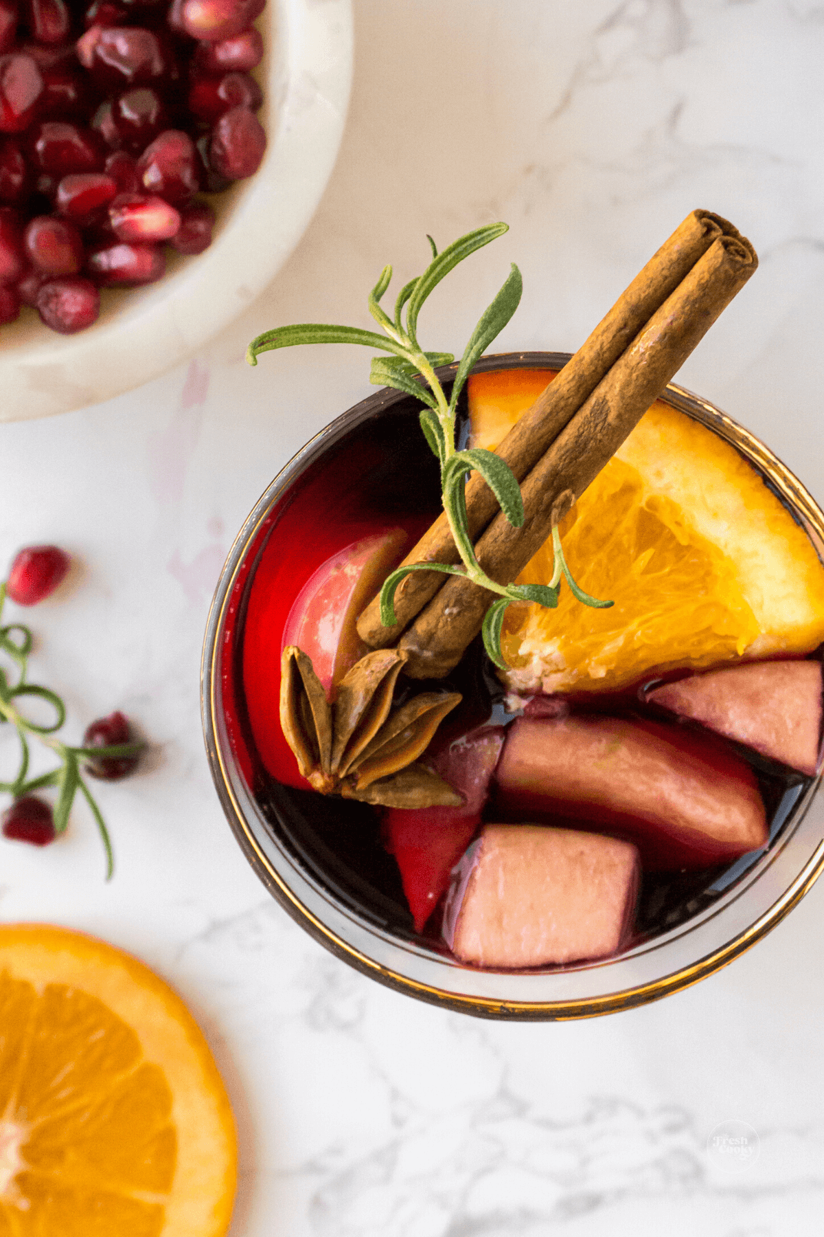 Glass full of fruit, topped with cinnamon spice, anise and rosemary.