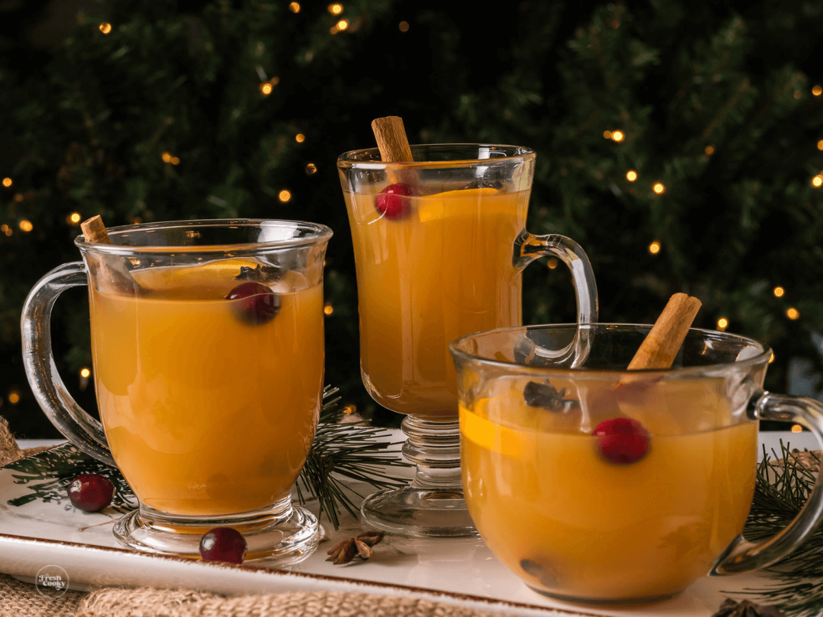Hot Wassail mulled cider in glass mugs in front of the Christmas tree.