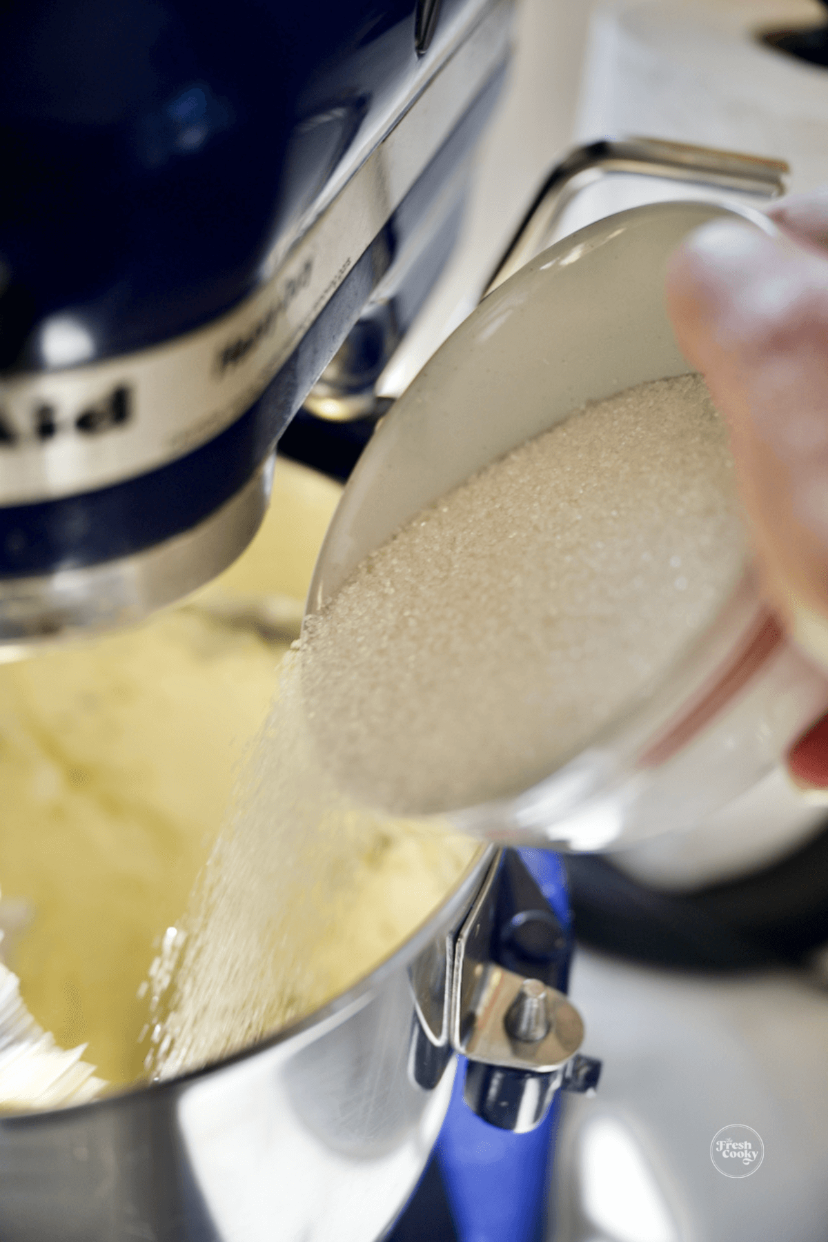 Adding sugar into light and fluffy butter and cream cheese mixture.