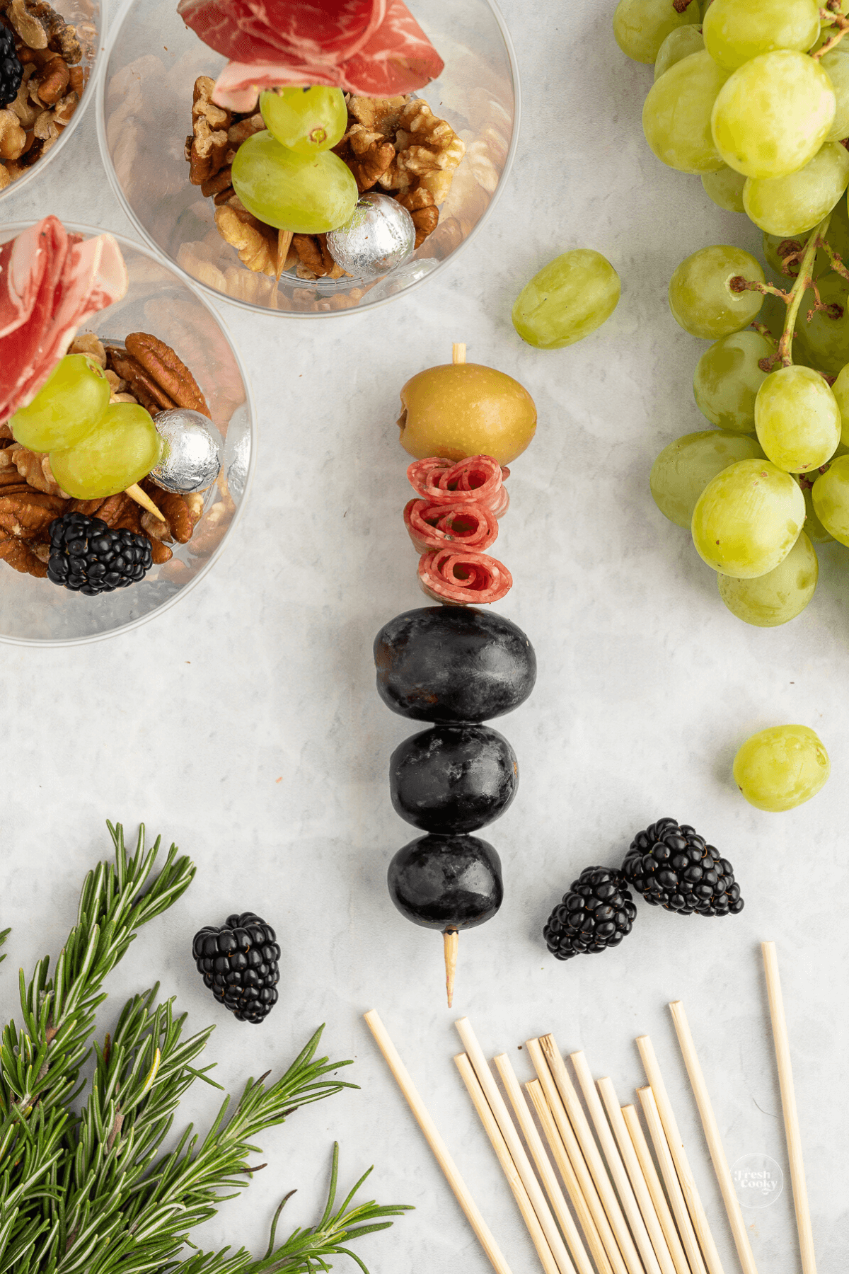 Olives, grapes, meat and green olive on skewer to place in charcuterie cup. 