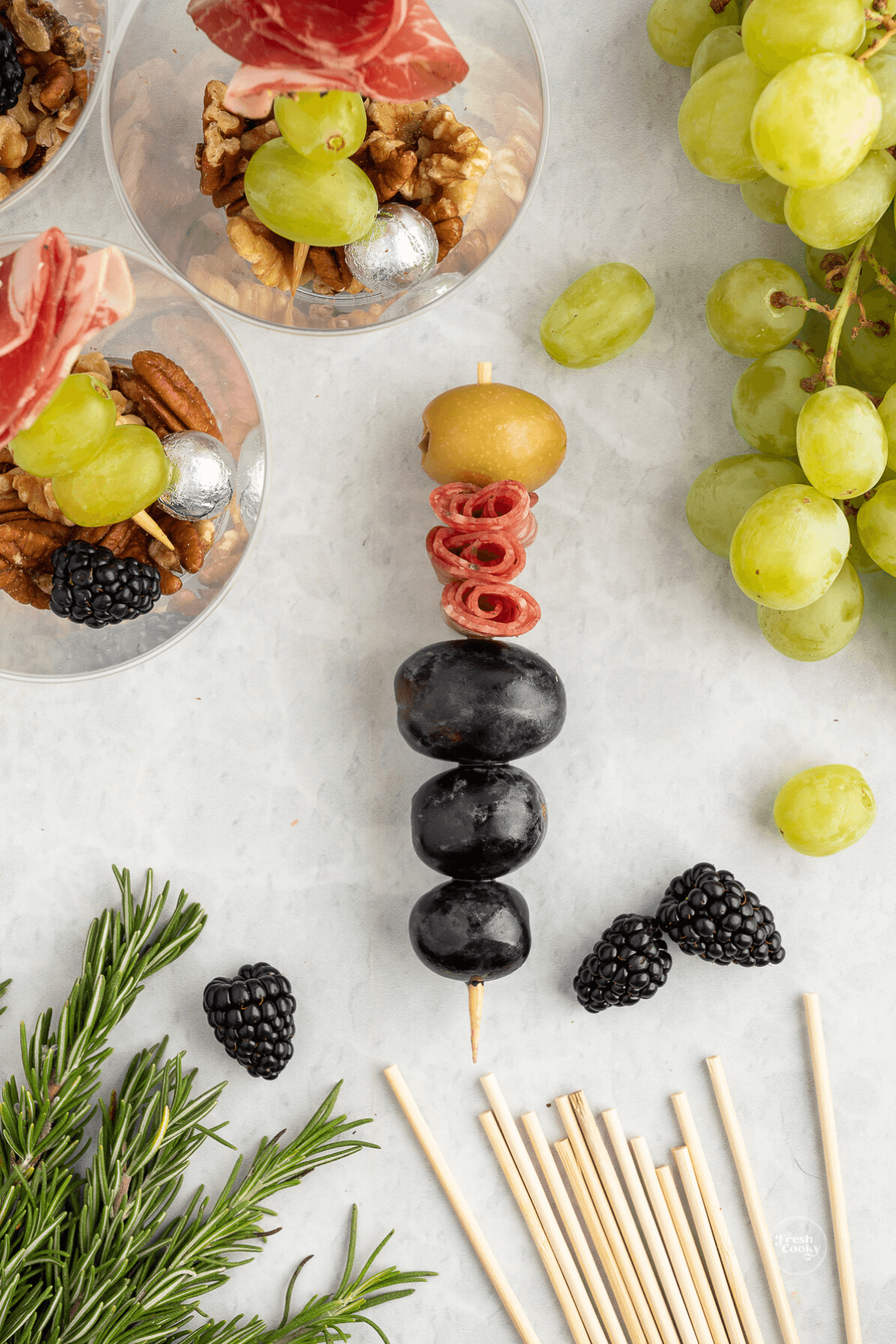 Olives, grapes, meat and green olive on skewer to place in charcuterie cup.