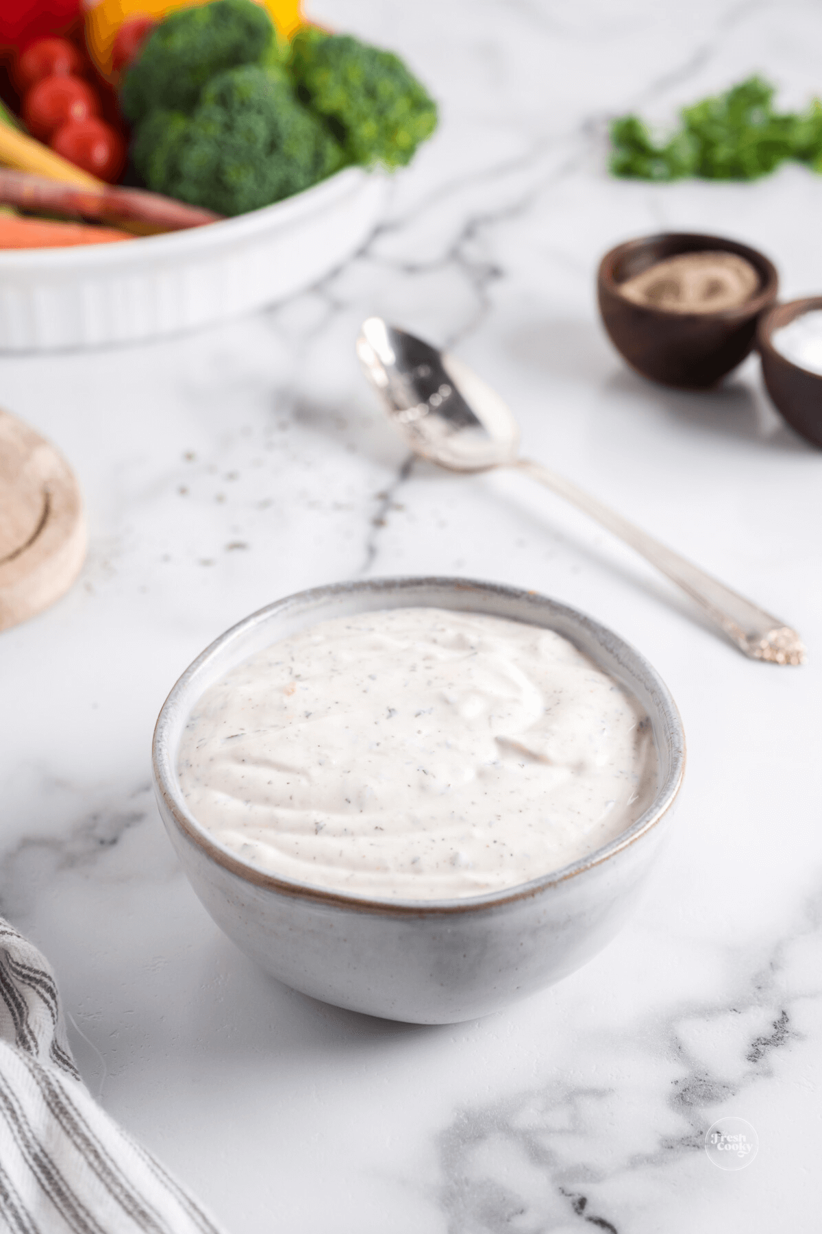 Veggie dip recipe in bowl with platter of veggies in background.