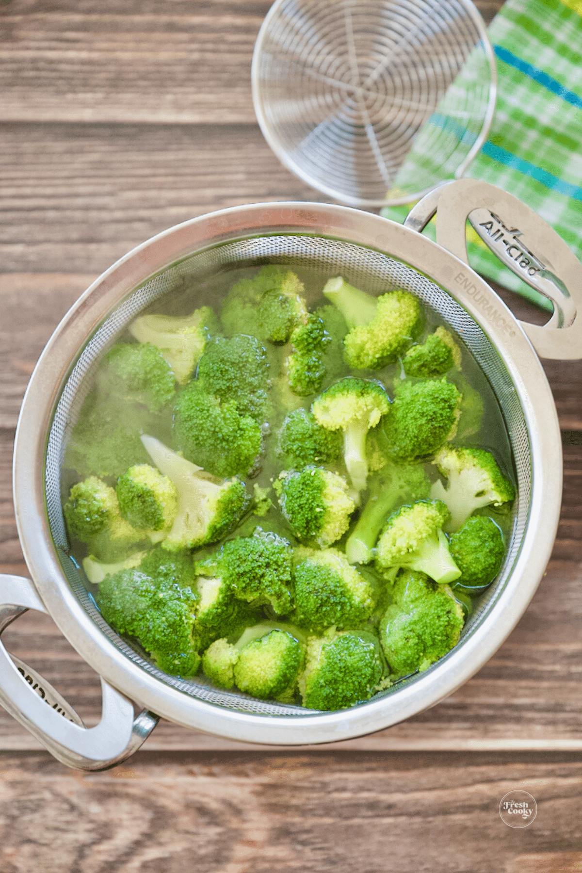 Broccoli florets in boiling water in steaming basket.