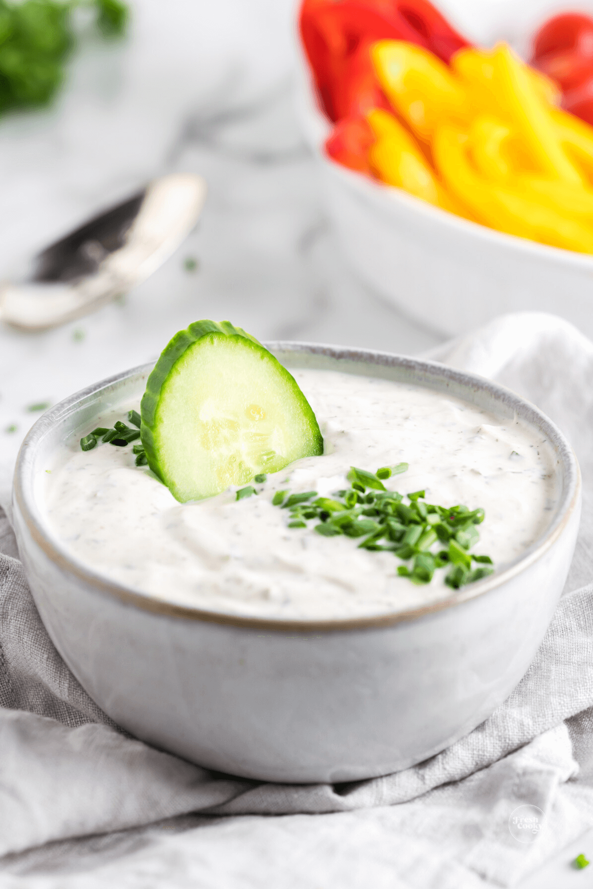 Best crudite dip in a bowl with a cucumber slice dipped in.