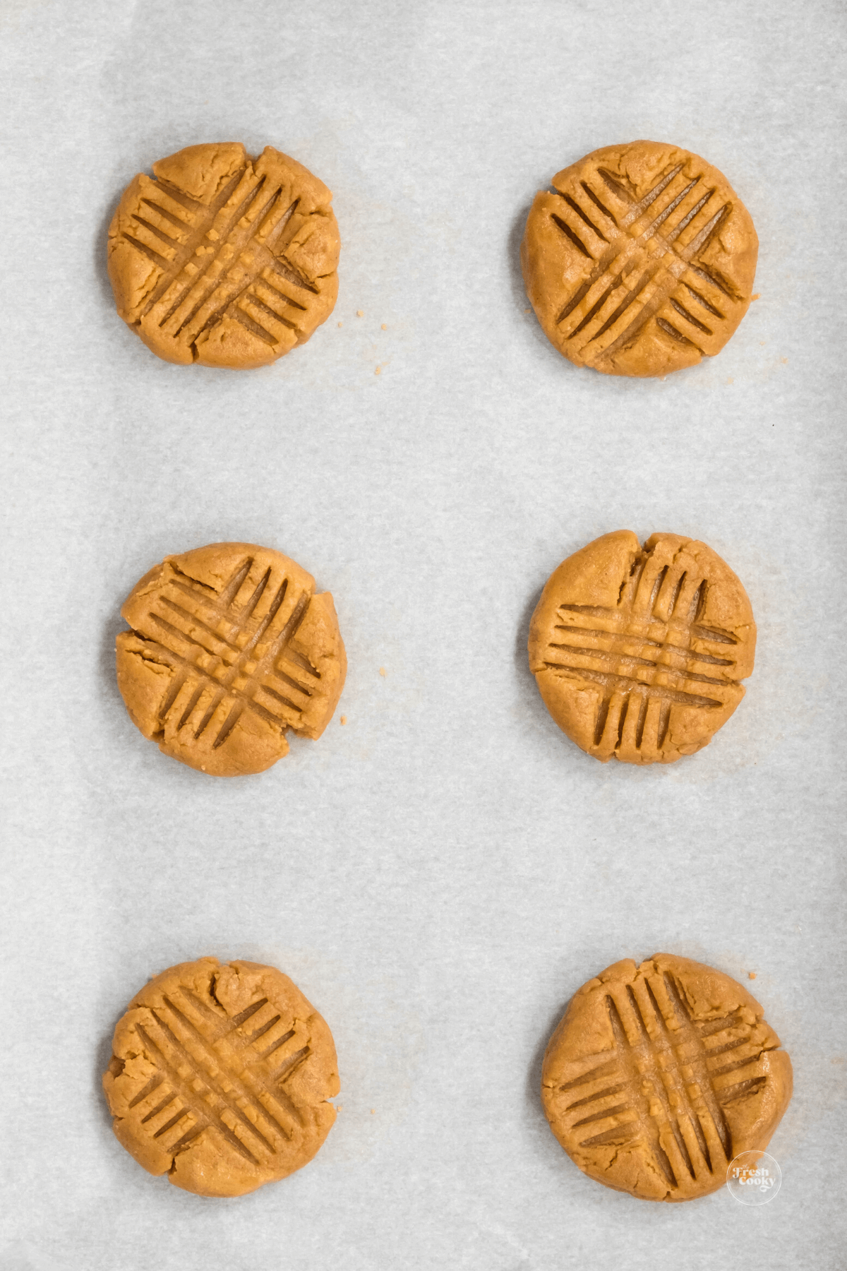 Peanut butter cookies on baking sheet with parchment paper.
