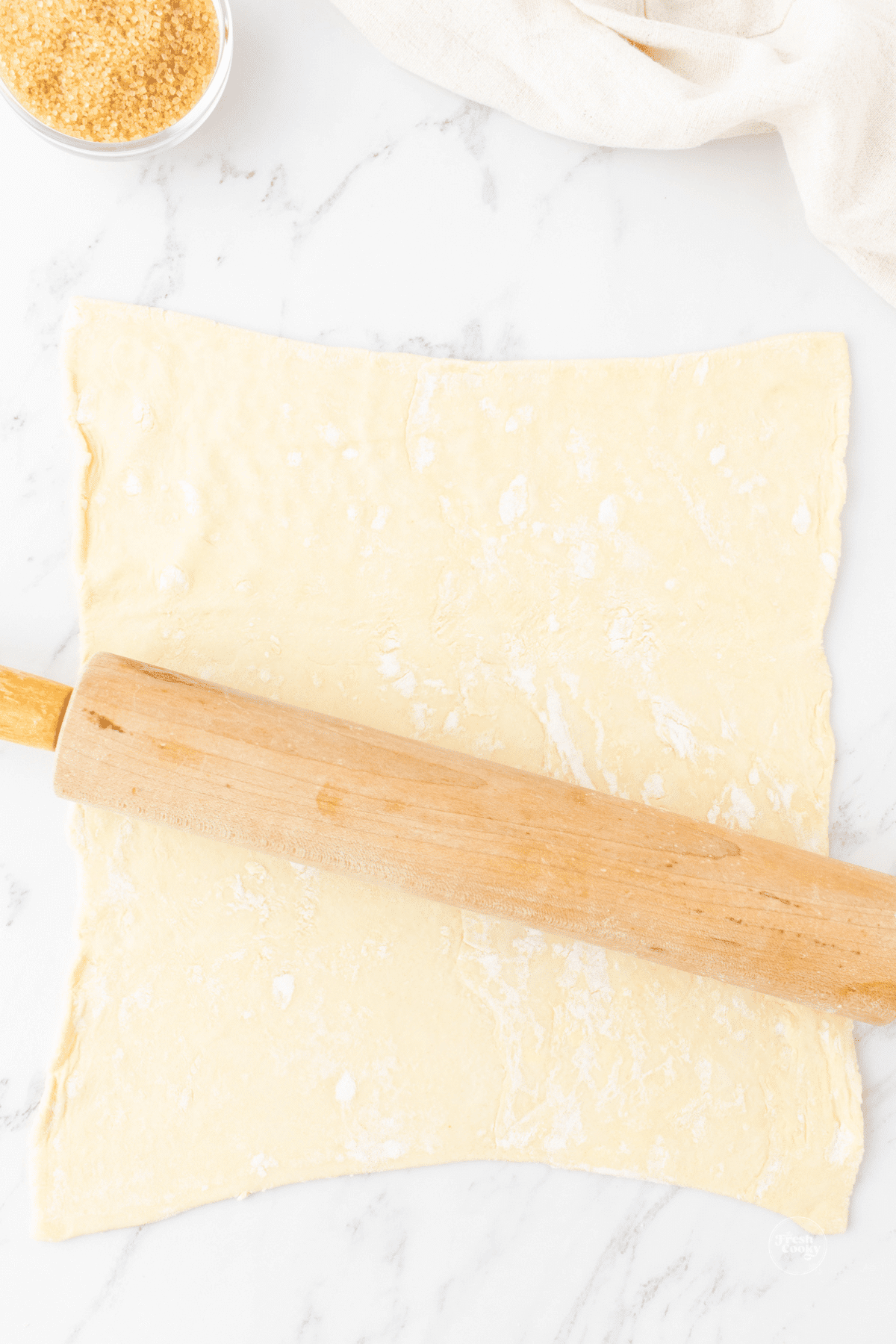 Rolling out puff pastry sheets slightly.