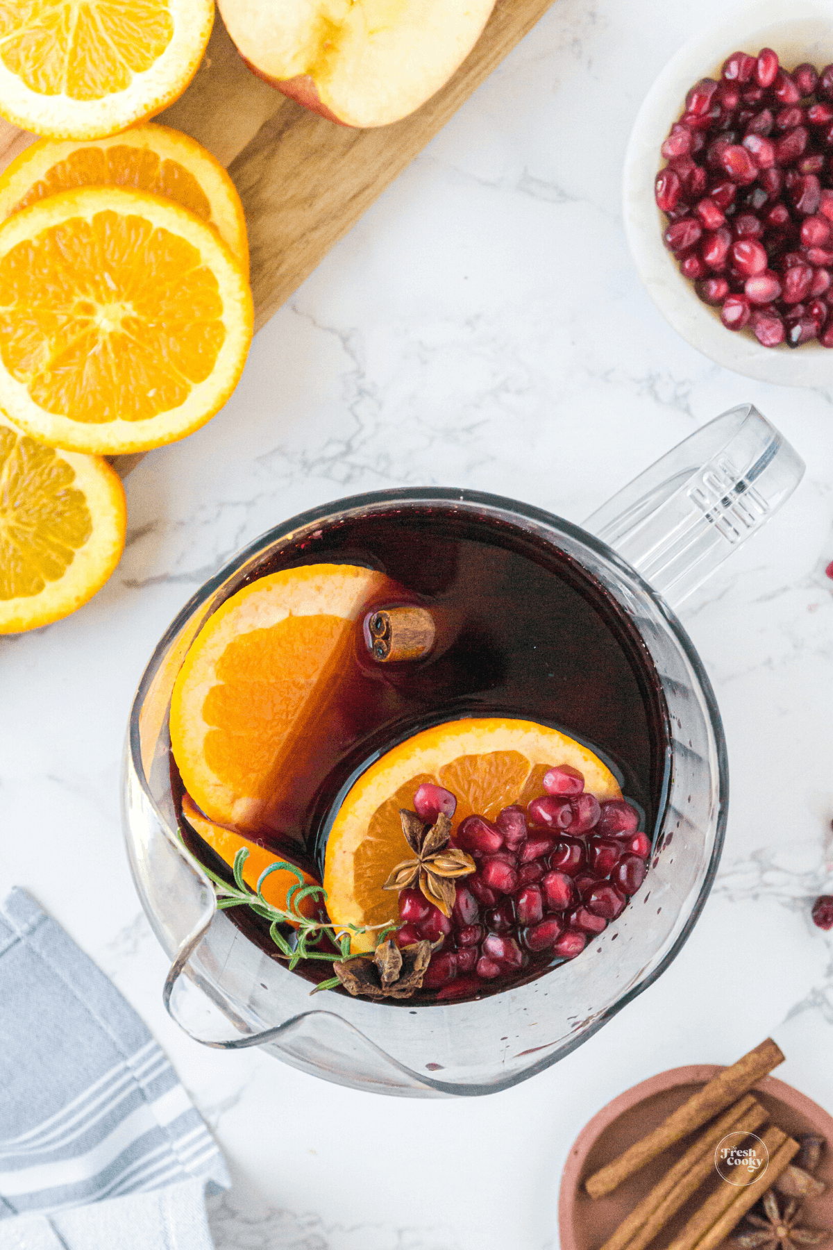 Pitcher filled with spiced holiday sangria with fruit slices ready for garnish.