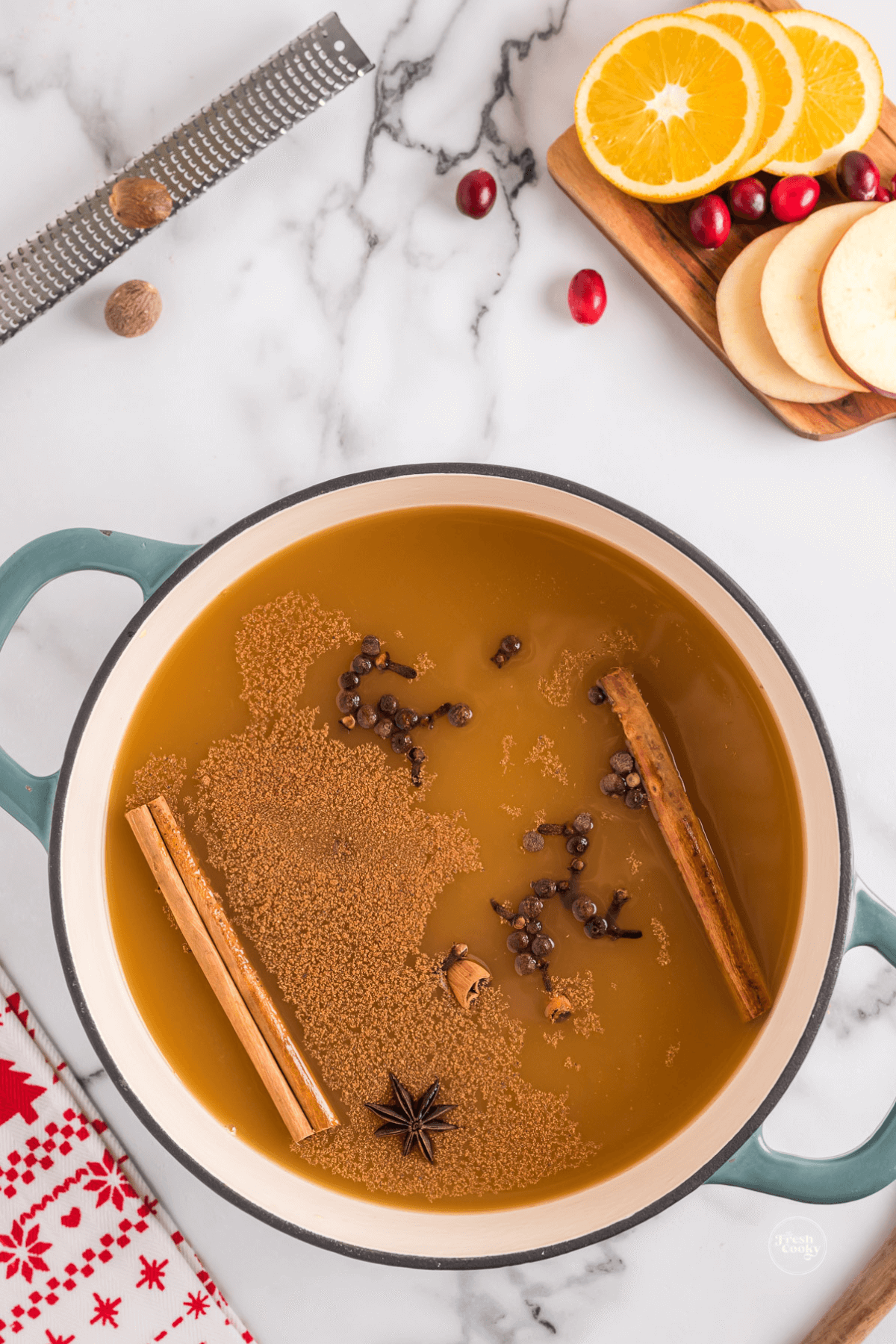 Adding spices to the juices for wassail in the pot. 