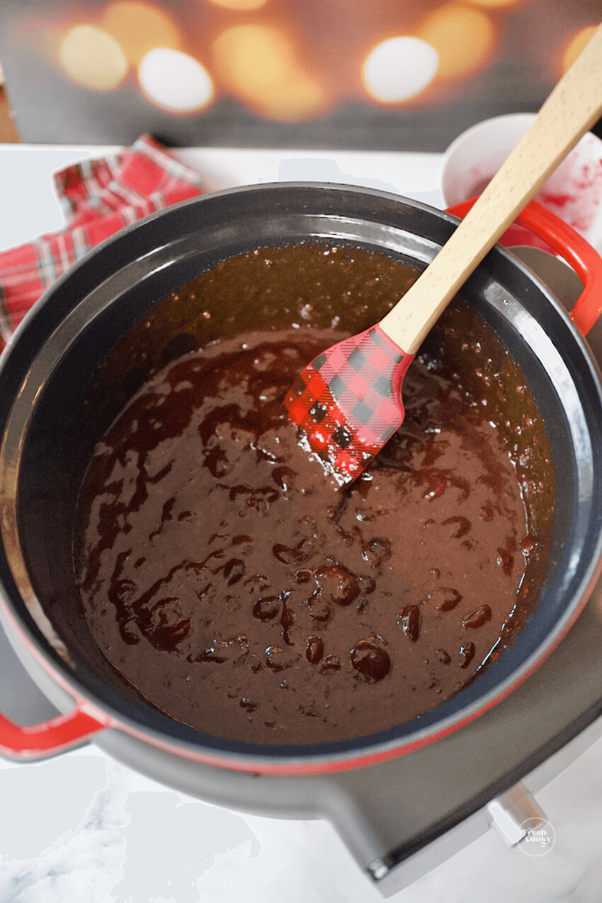 Stirring together barbecue sauce and cranberry sauce for meatballs. 