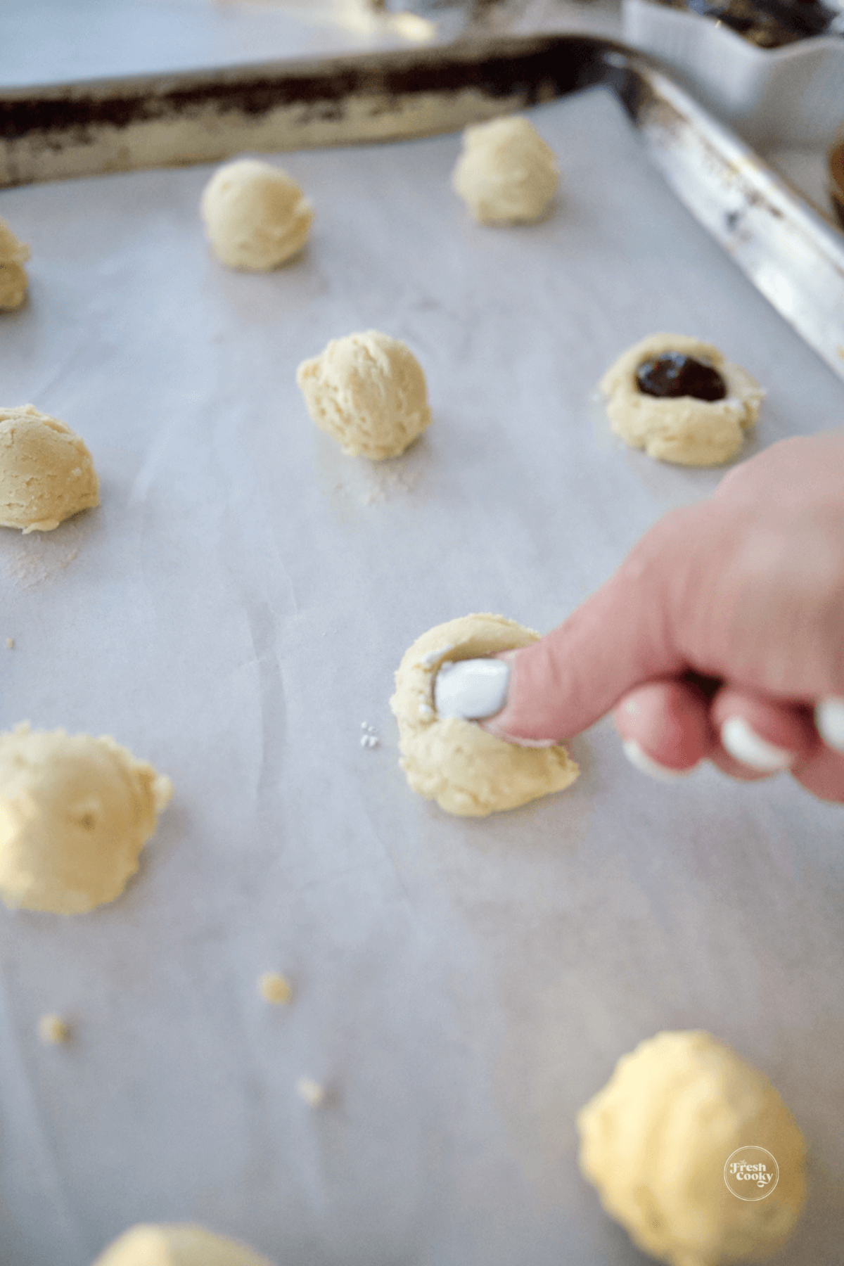 using thumb to press indent into center of cookie. 