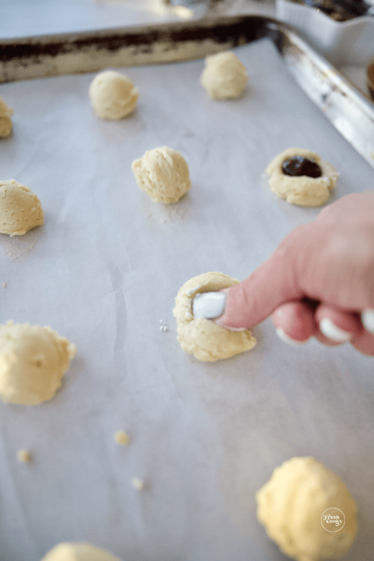 using thumb to press indent into center of cookie.