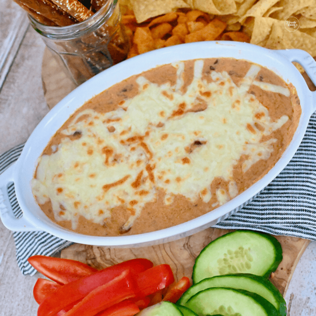 3 Ingredient chili cheese dip in baking dish surrounded by dipping veggies, pretzels, tortilla chips and fritos.