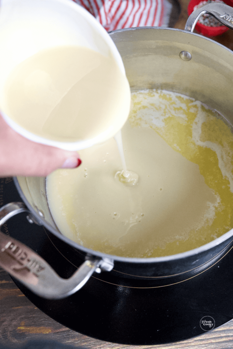 Pouring in sweetened condensed milk into melted butter in saucepan.