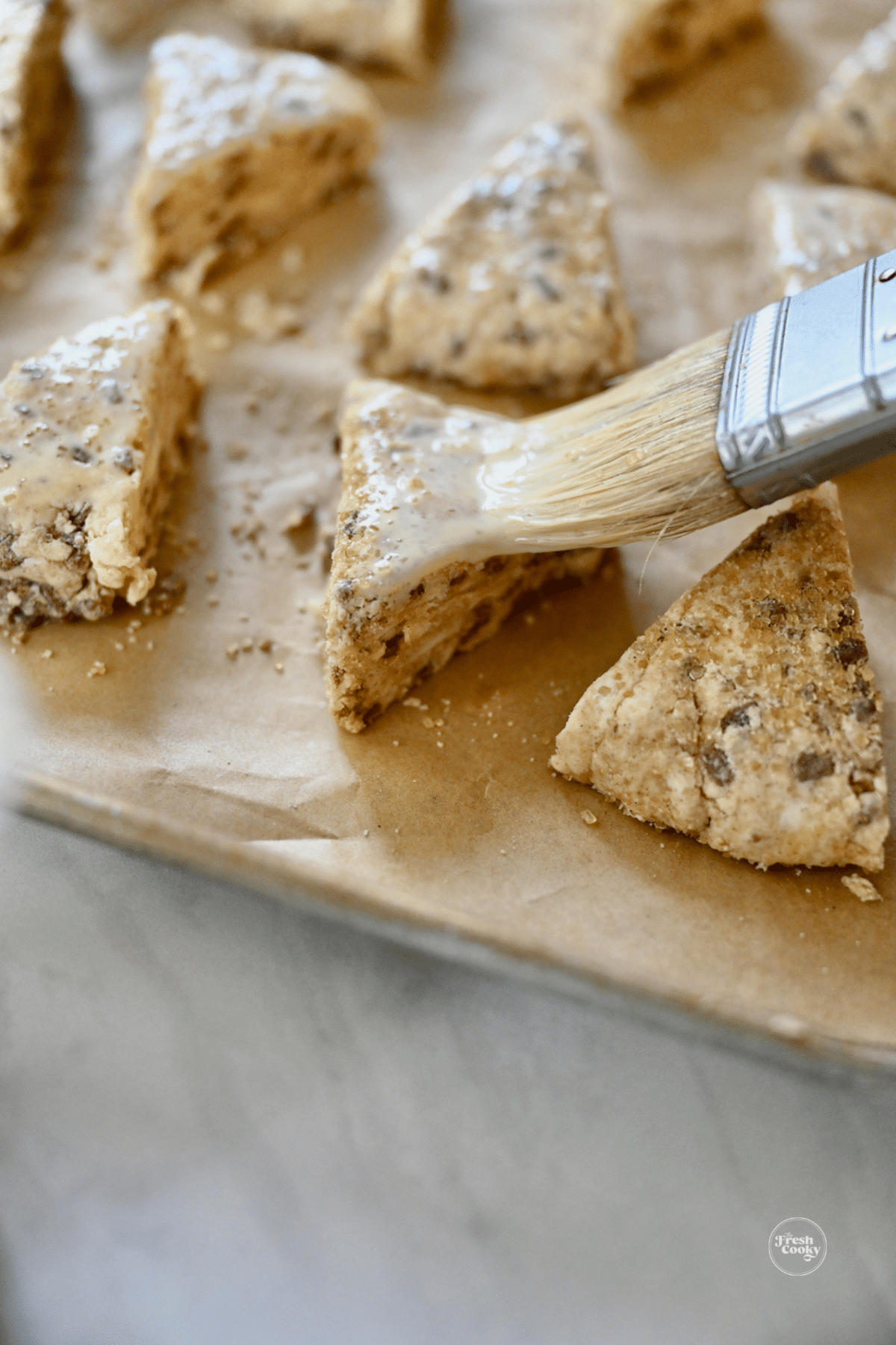 Brushing scones with egg and cream wash before baking.