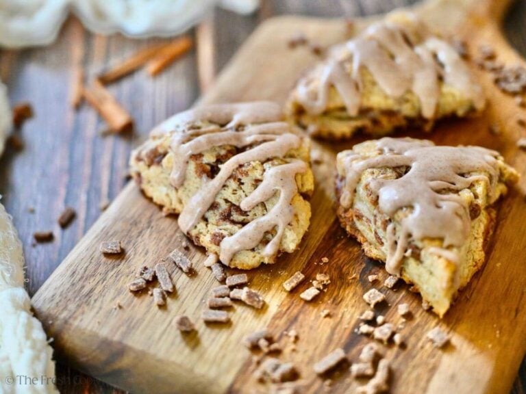 Cinnamon Chip Scones on a cutting board with cinnamon chips laying around.