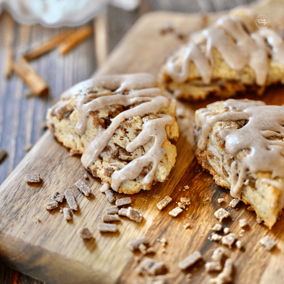 Cinnamon Chip Scones on a cutting board with cinnamon chips laying around.