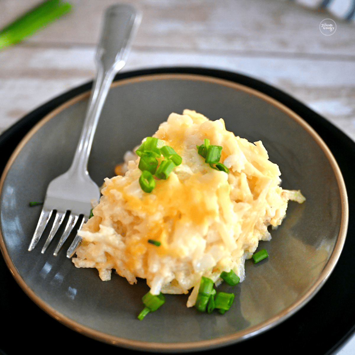 Serving of Cracker Barrel Hashbrown casserole on a plate with a fork.