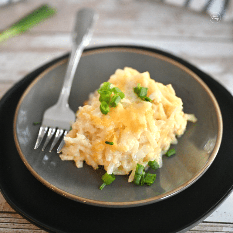 Serving of Crockpot Cracker Barrel Hashbrown Casserole on a gray plate.