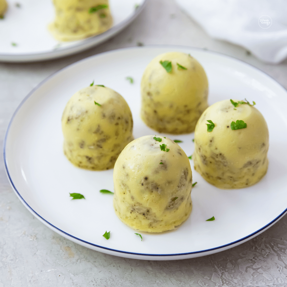 Instant Pot egg bites on a plate with another plate behind with a few egg bites.