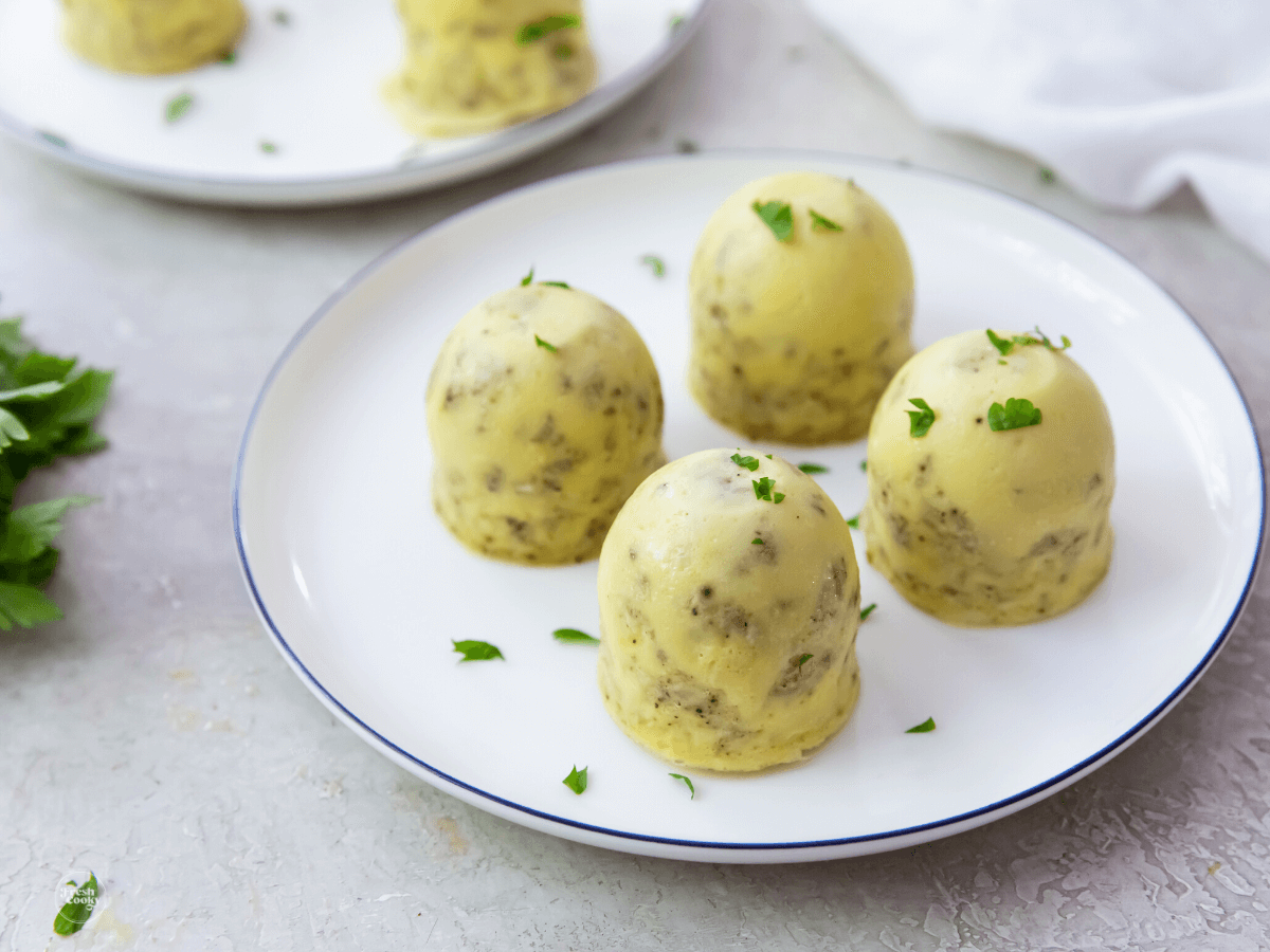 Instant Pot egg bites on a plate with another plate behind with a few egg bites on it.