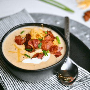 Copycat Outback Loaded Baked Potato soup in bowl topped with bacon, cheese, chives and sour cream.