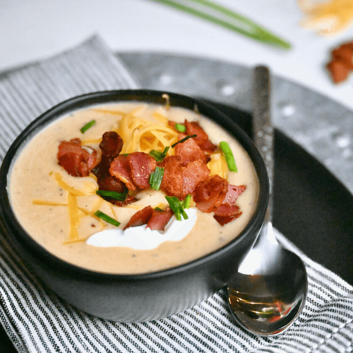 Copycat Outback Loaded Baked Potato soup in bowl topped with bacon, cheese, chives and sour cream.