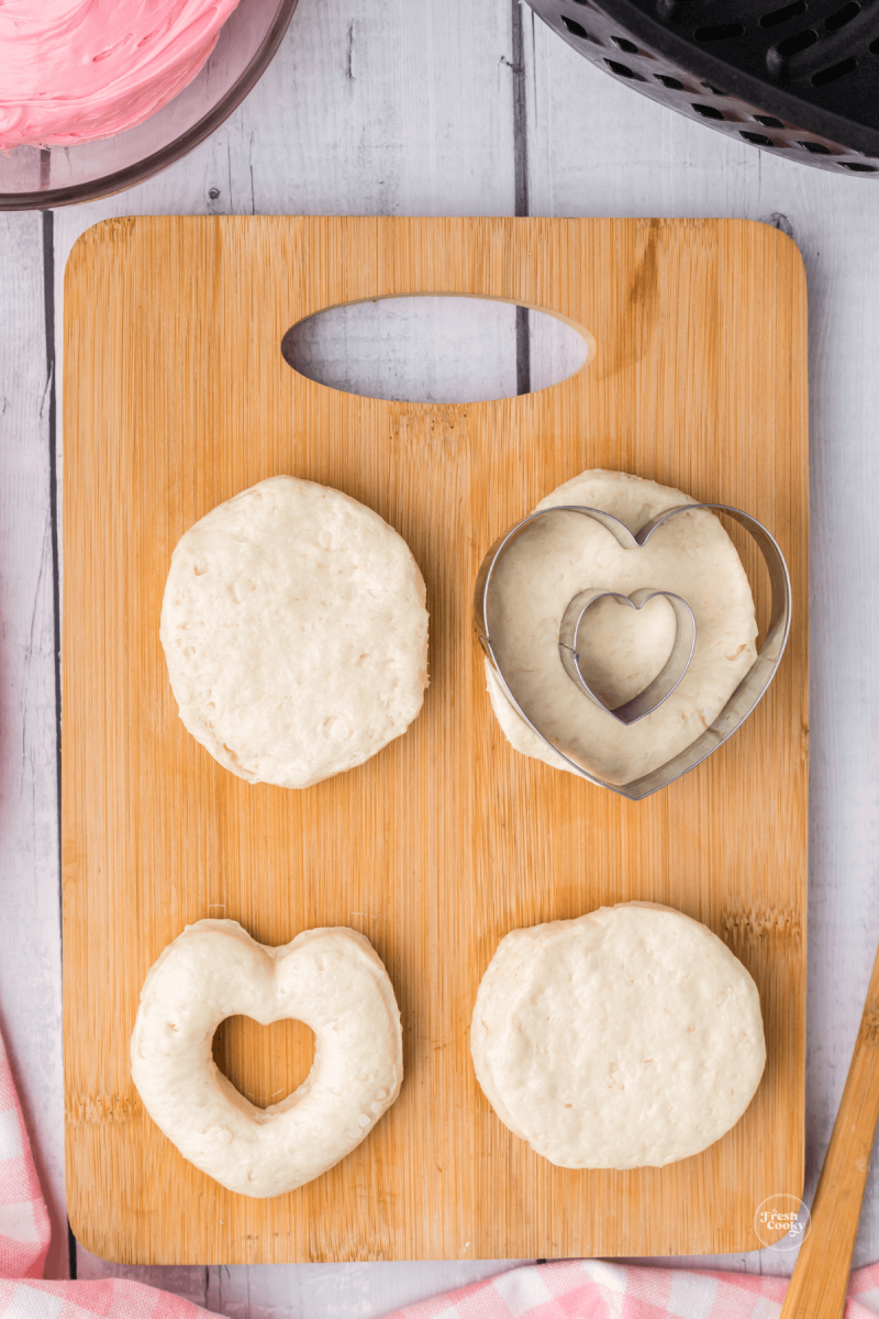 Biscuit dough with various stages of cutting out heart shaped biscuit dough. 