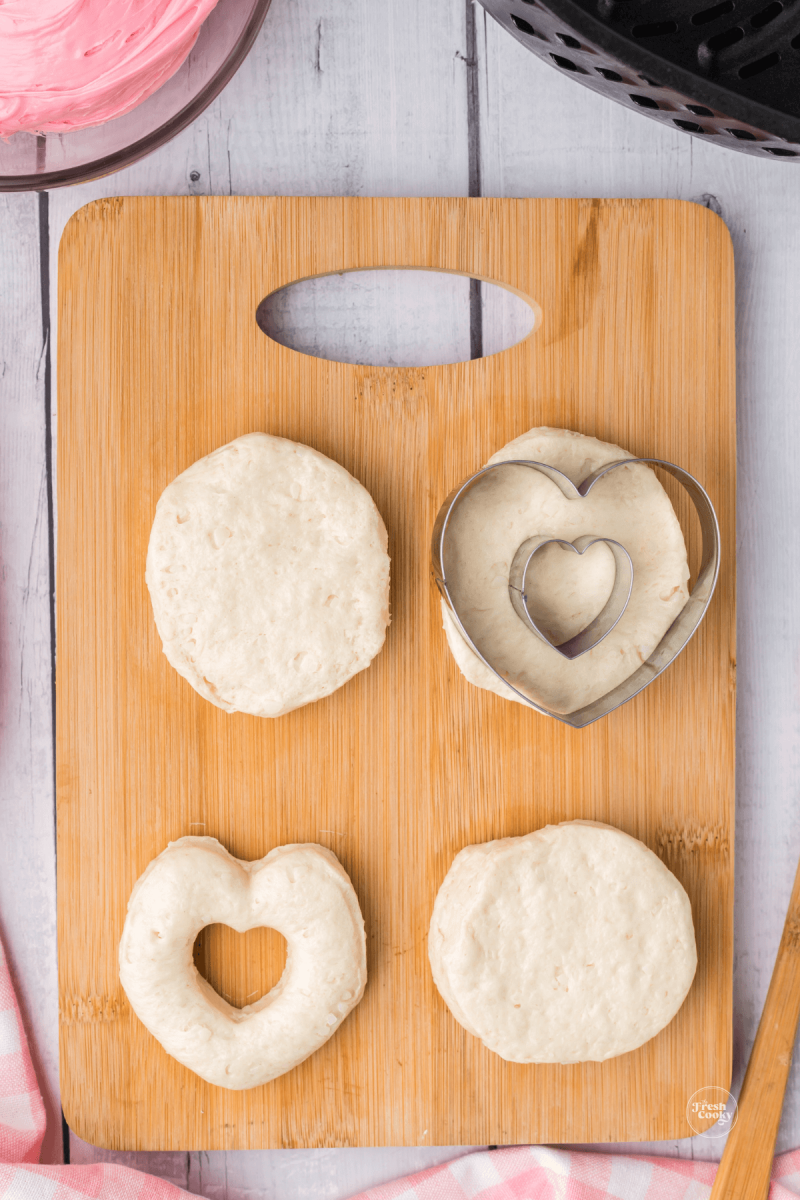 Biscuit dough with various stages of cutting out heart shaped biscuit dough.