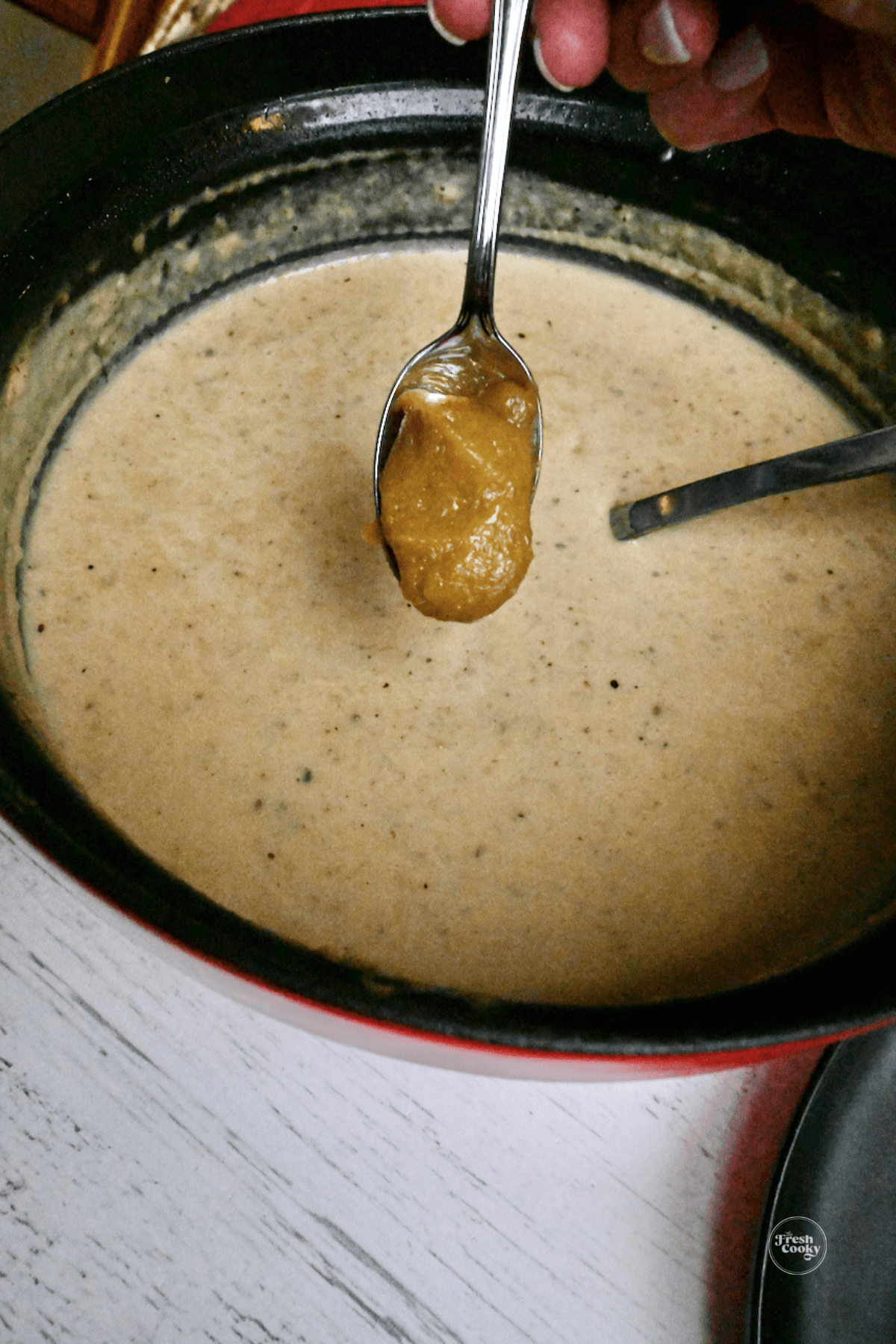 Adding chicken bouillon to potato soup.