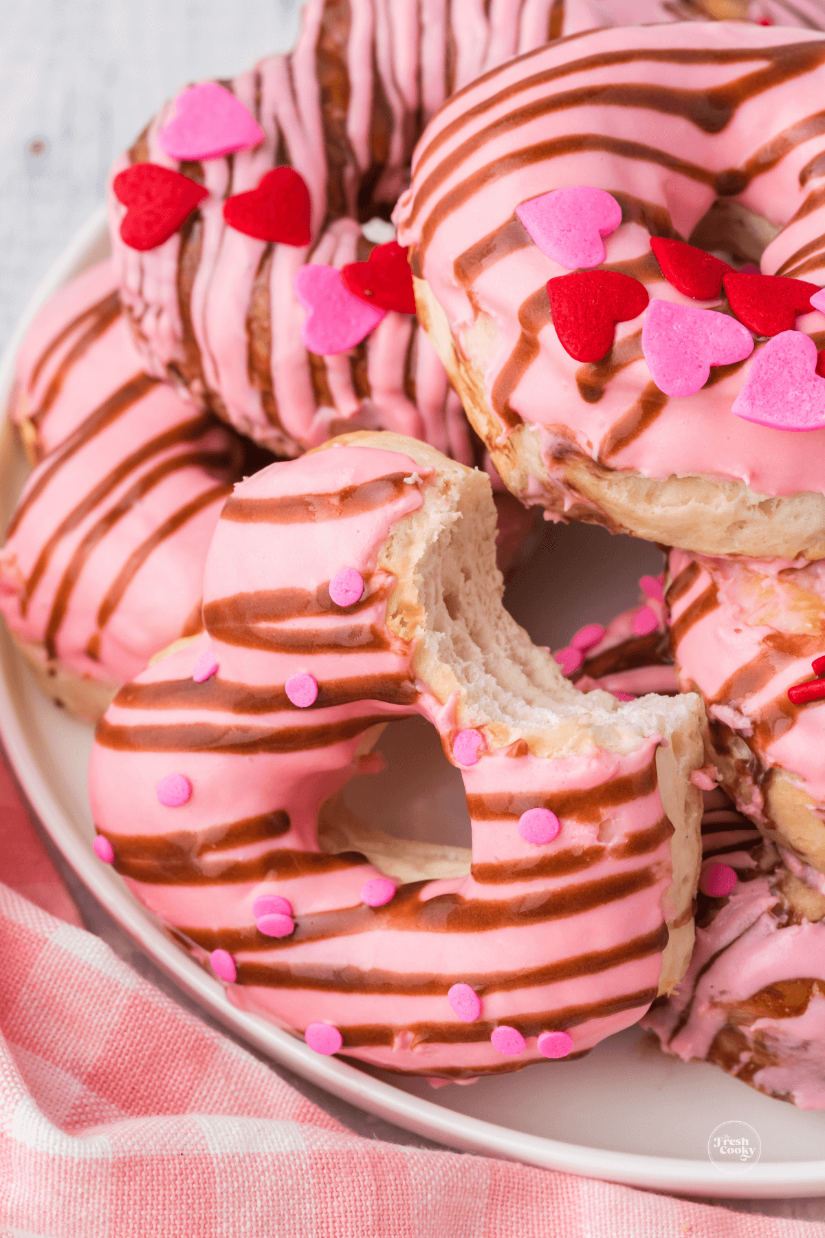 Plate filled with heart shaped biscuit donuts one with bite taken out.