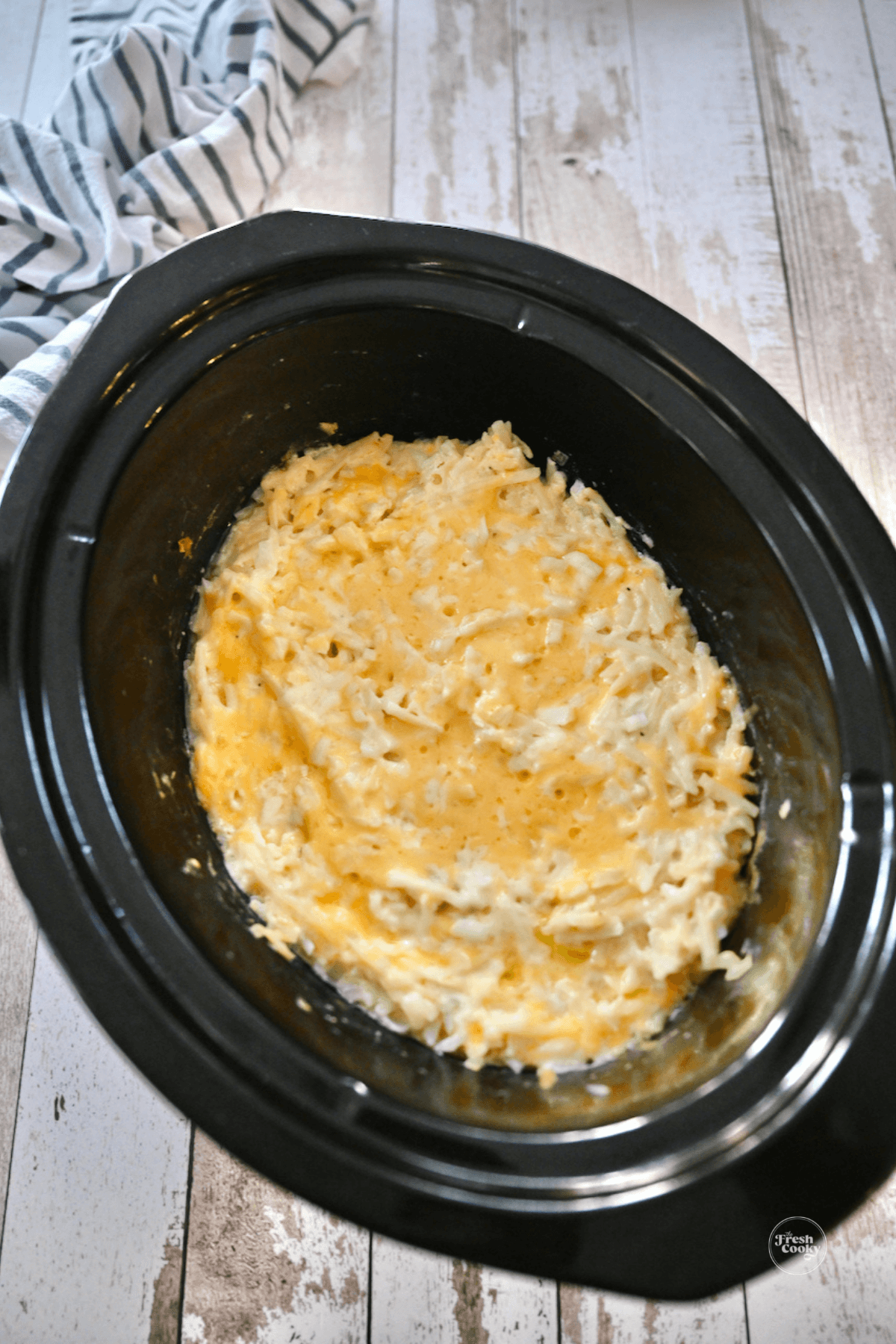 Cooked, cheesy cracker barrel hashbrown casserole in crockpot ready to serve.