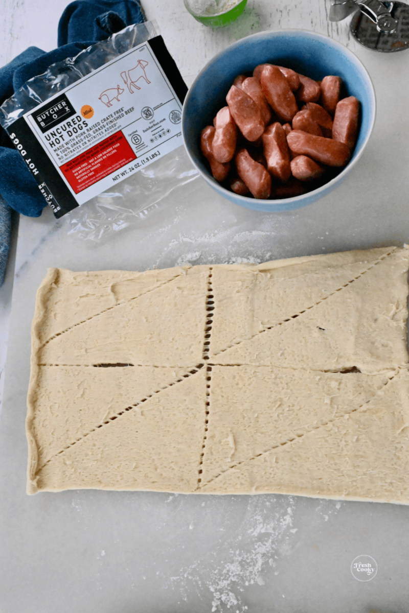 Opened roll of of crescent roll dough, little smokies.