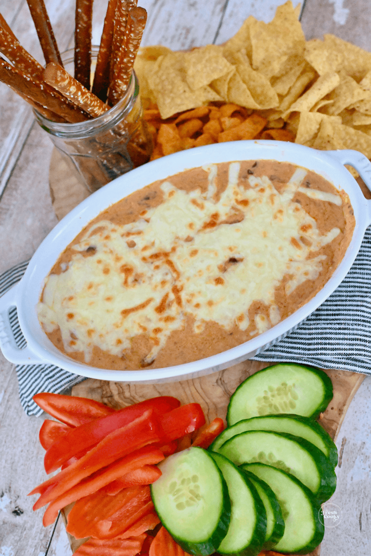 3 ingredient chili cheese dip in baking dish topped with melted cheese and served with an assortment of veggies and chips. 