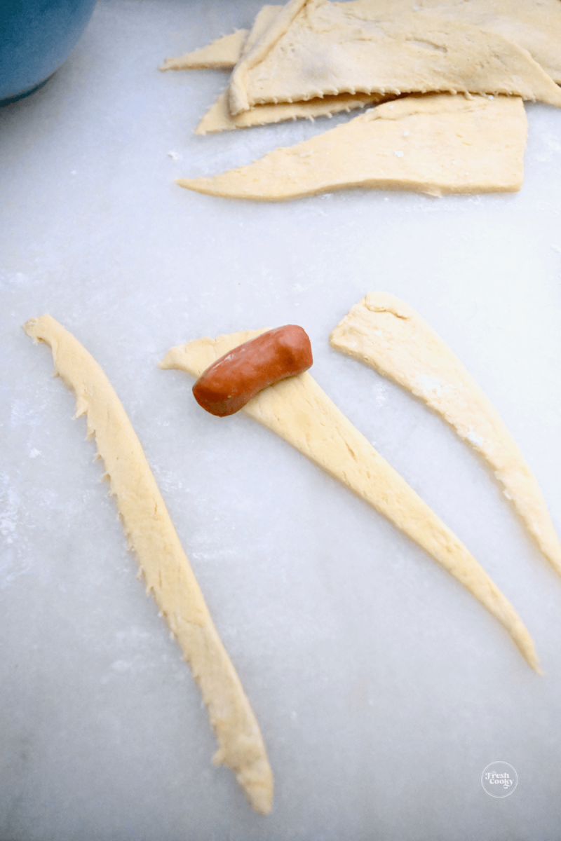 Place sausage on widest end of crescent strip.