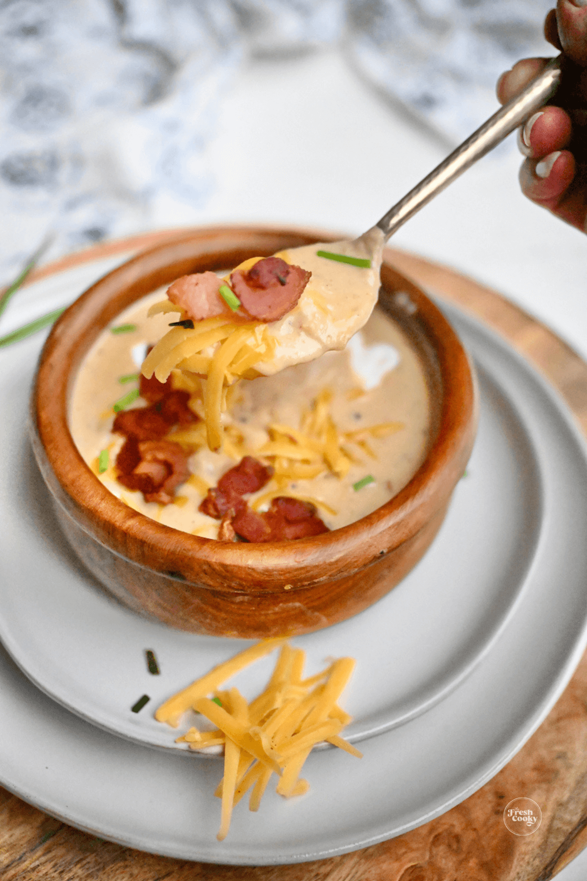 Spoonful of potato soup with melty cheddar cheese.