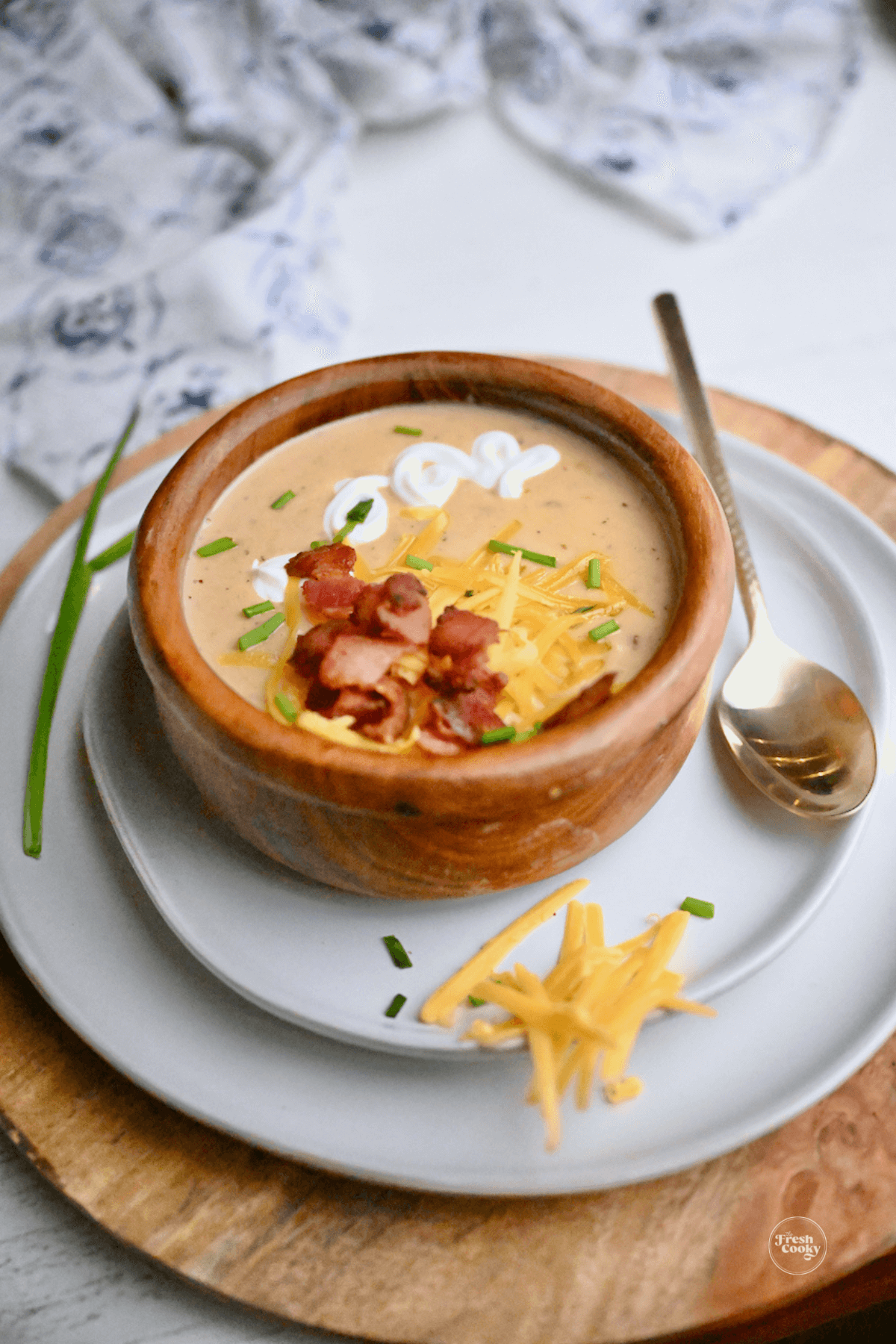 Potato soup in bowl topped with crisp bacon, sour cream and shredded cheddar cheese.
