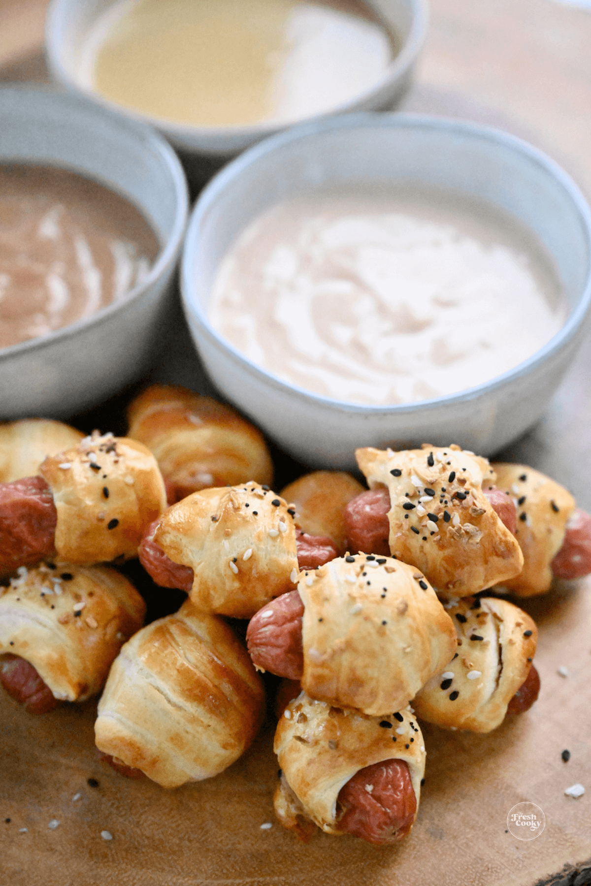 Pigs in a blanket on tray with dipping sauces.