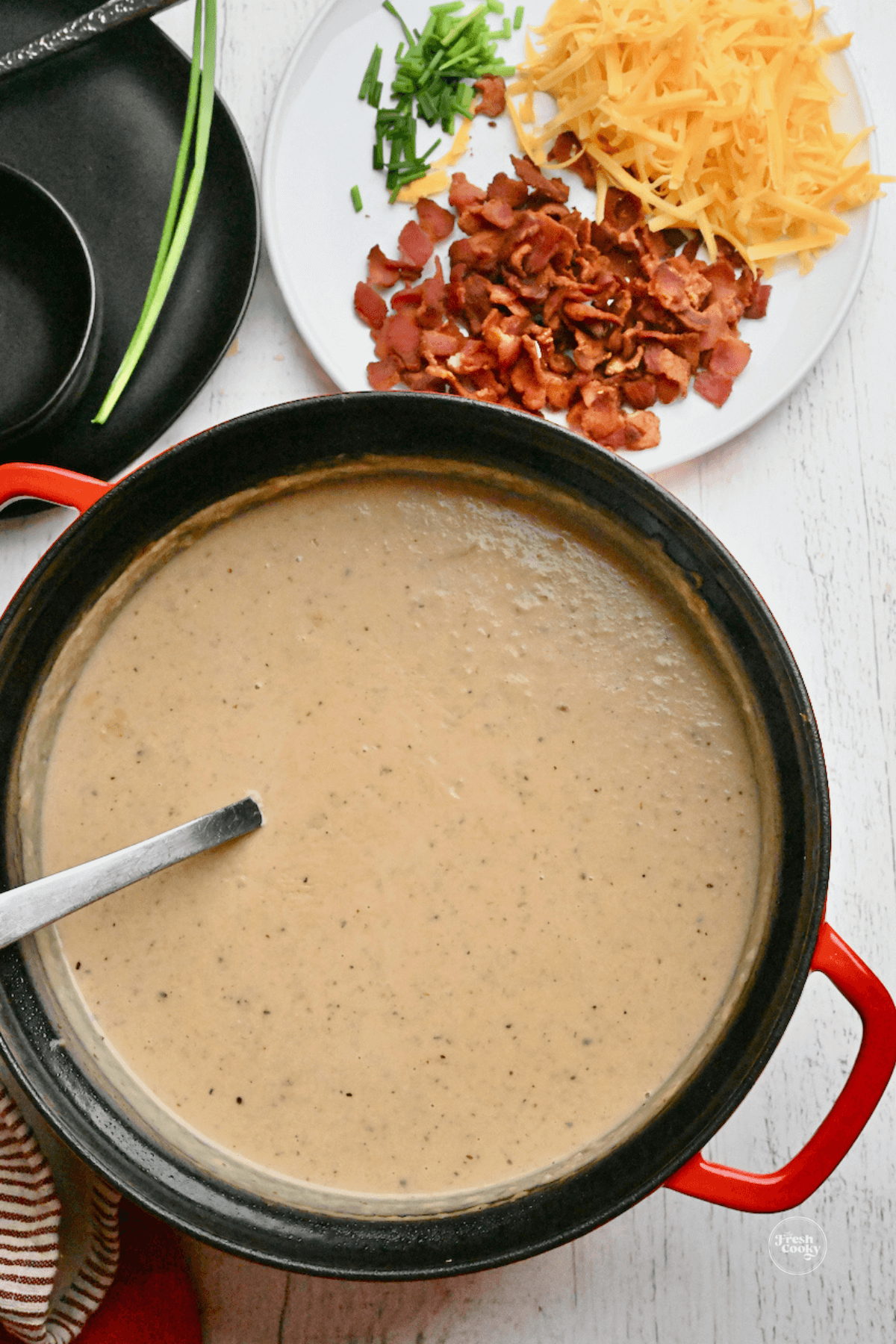 Outback Potato Soup in crockpot slow cooker with crispy bacon, shredded cheese and chives for garnish.