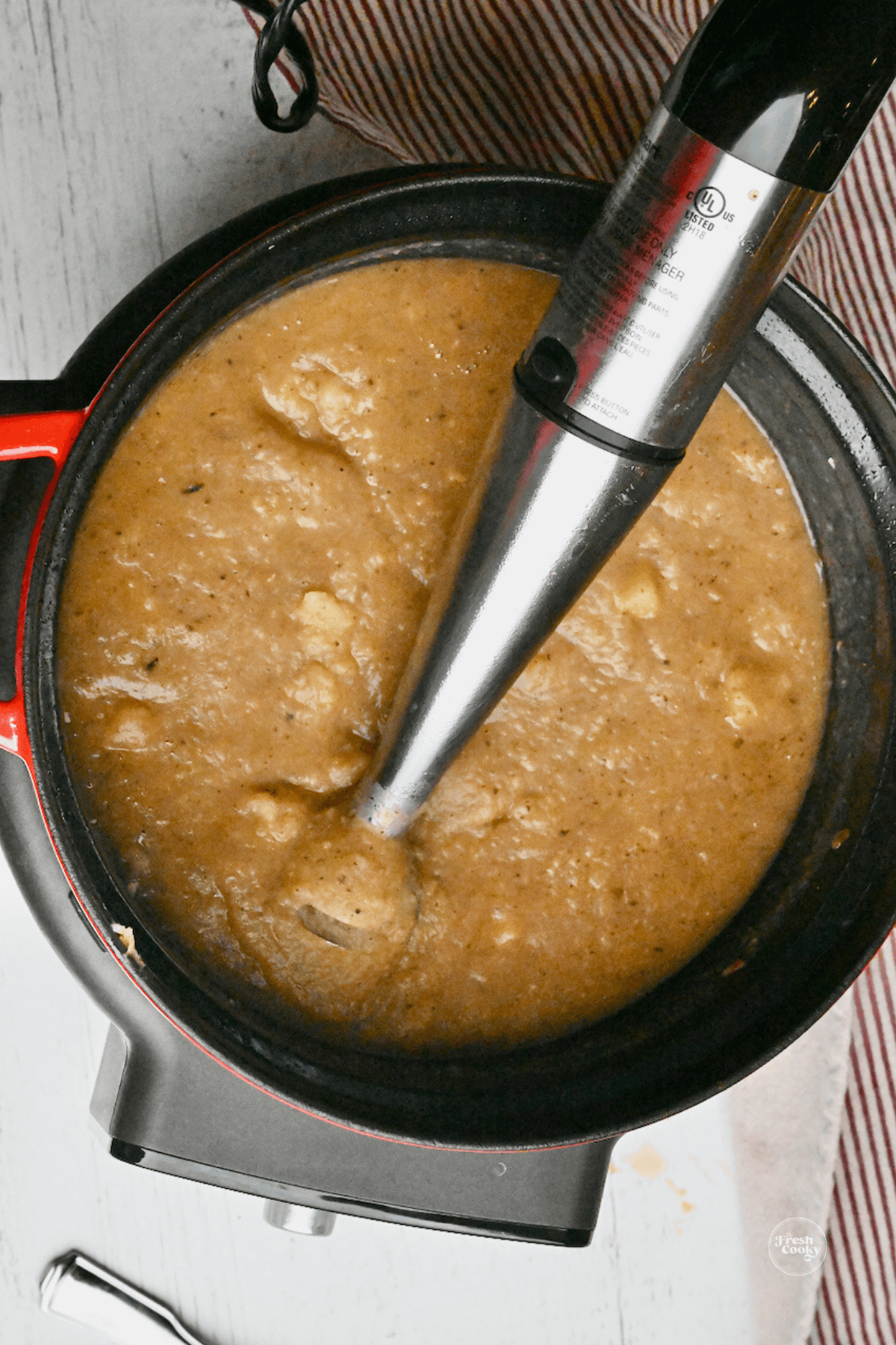 Immersion blender with mostly blended potato soup.