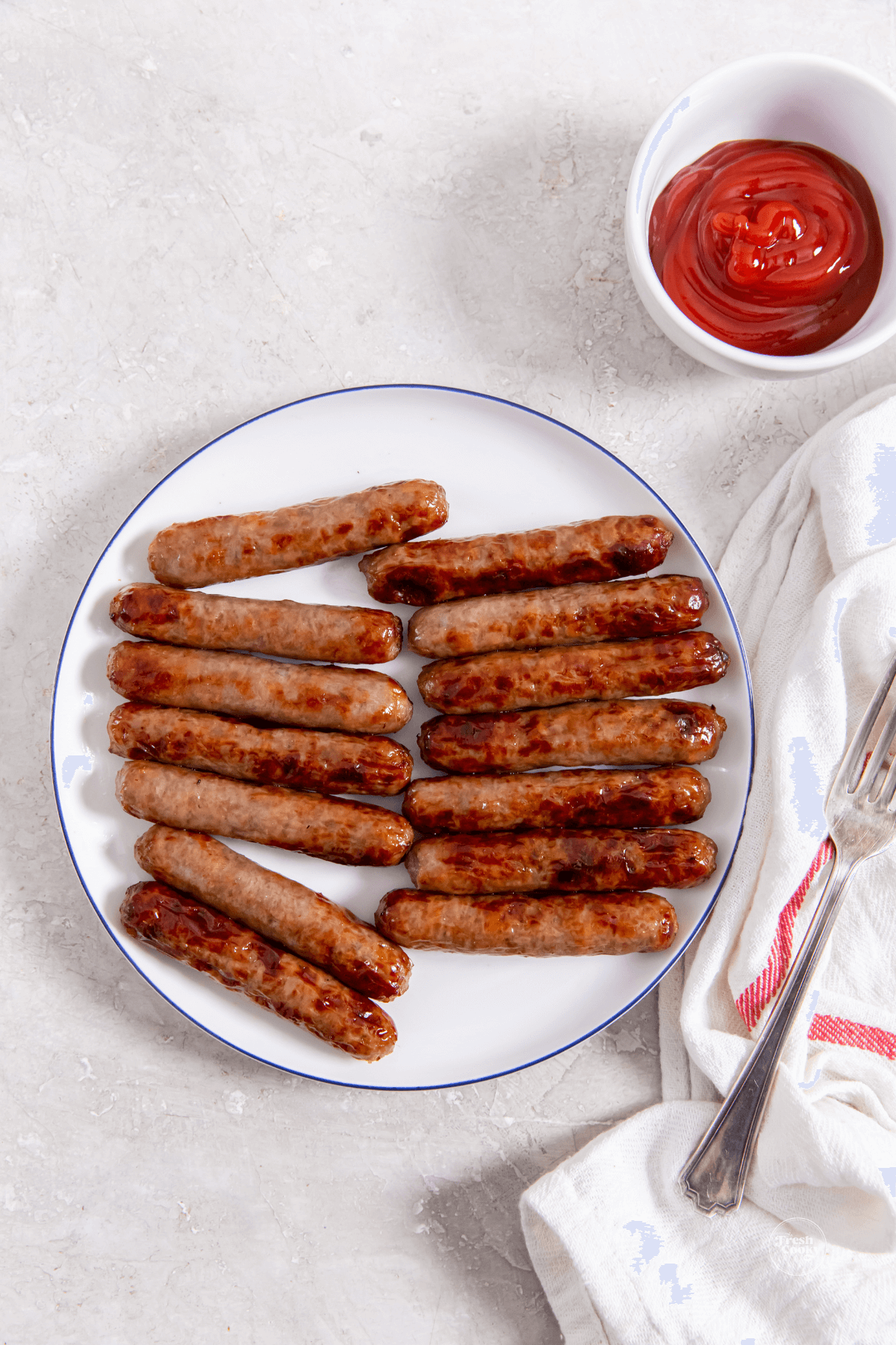 Breakfast sausage links on plate with a side of ketchup.