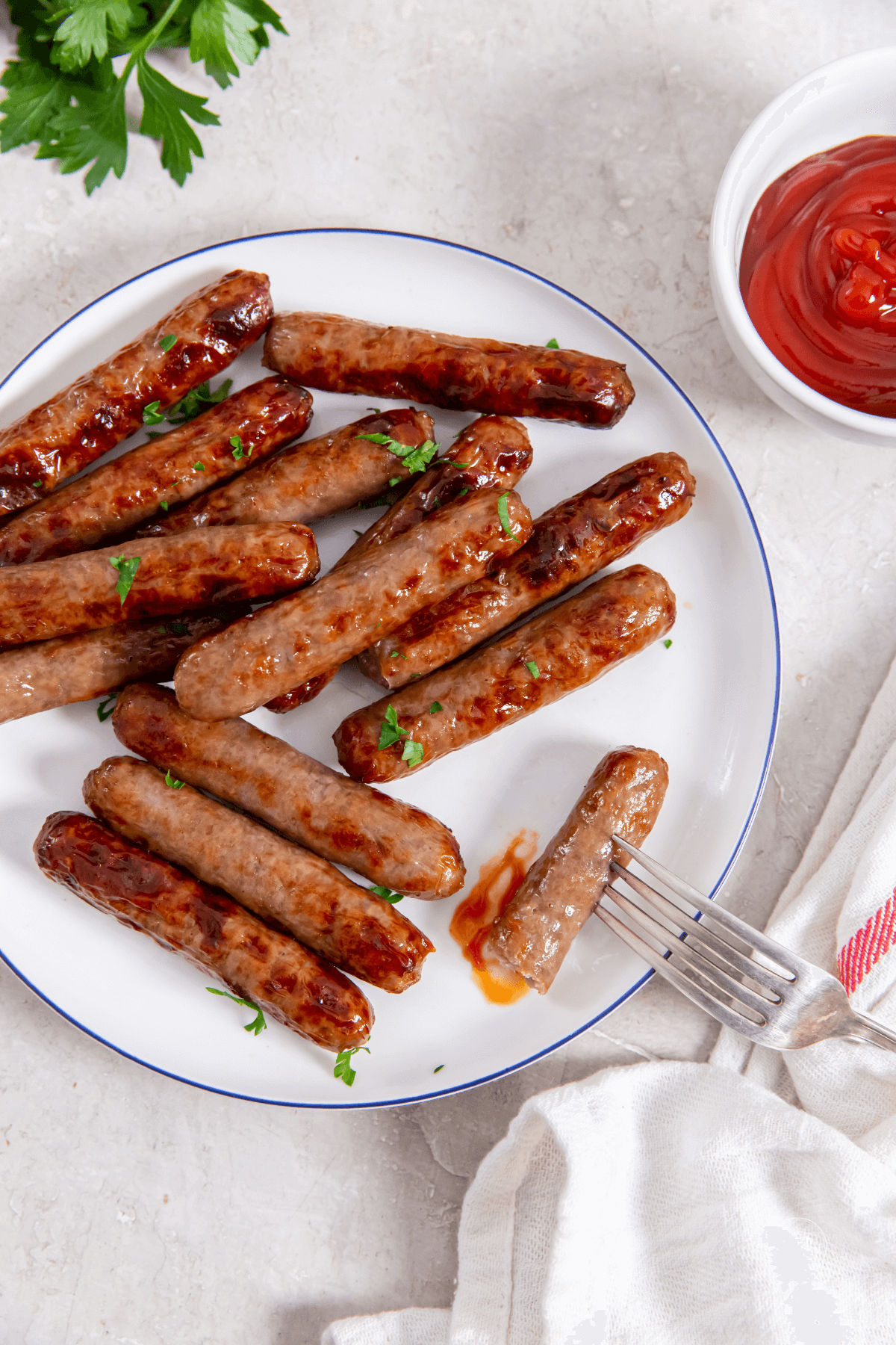 Sausage links made in air fryer on plate with ketchup.