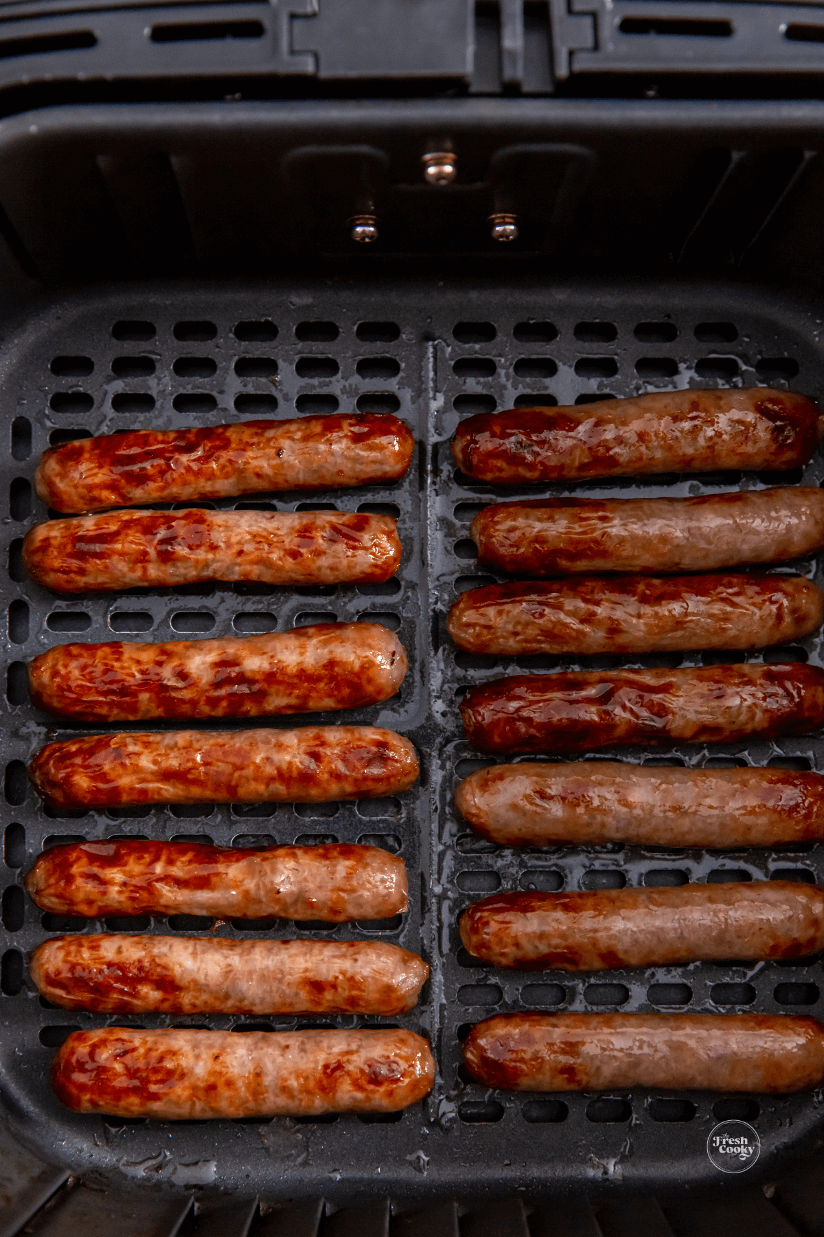 Cooked sausage links in air fryer basket.