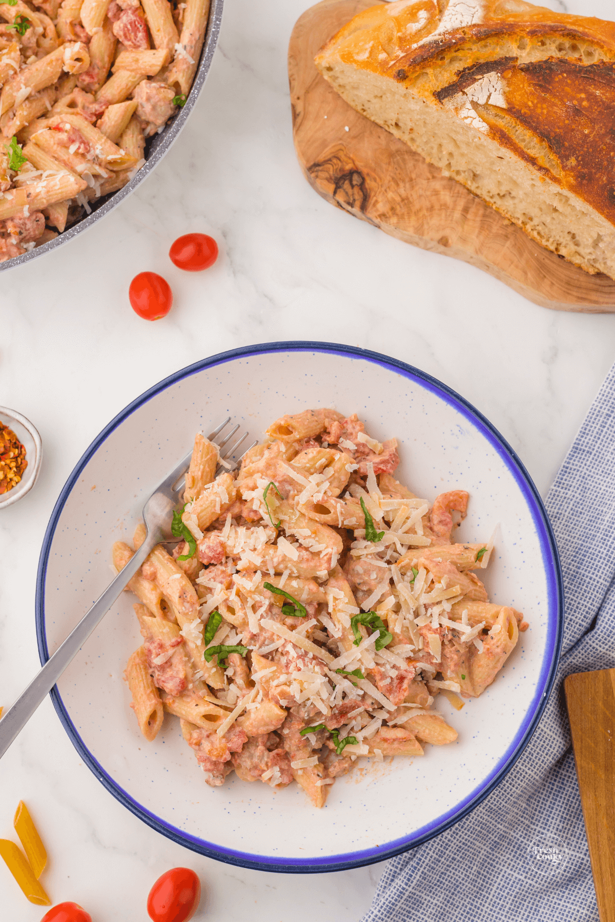 One pot creamy sausage pasta in bowl with bread in background.
