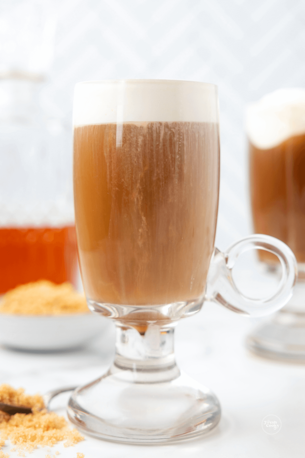 Easy Irish coffee recipe, in glass mugs with brown sugar and a decanter of whiskey in background.