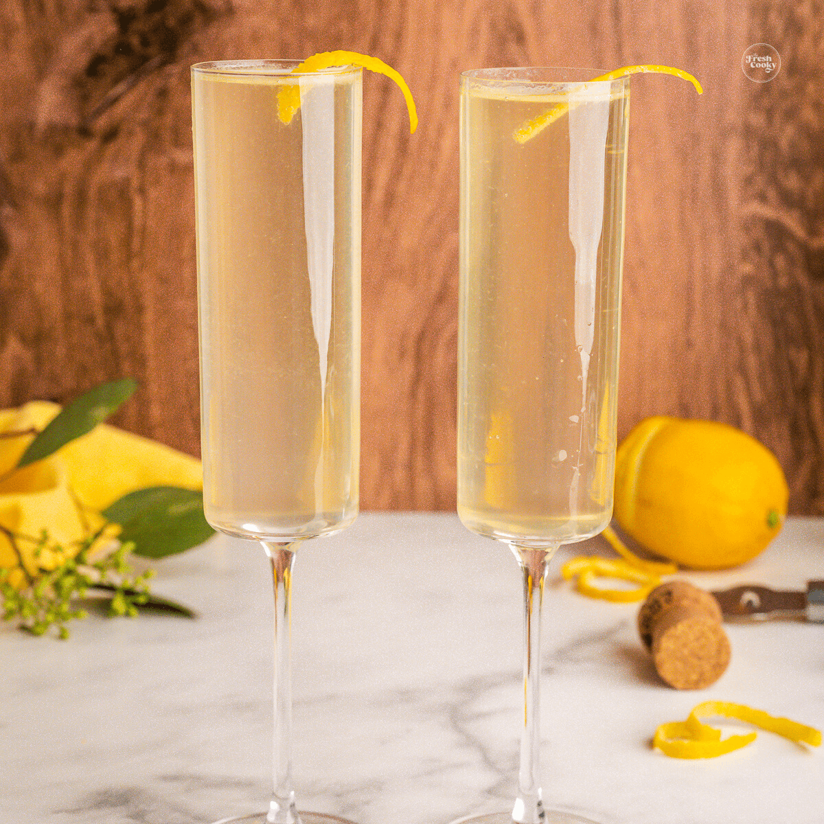 French 75 cocktail in champagne glasses garnished with a lemon twist.